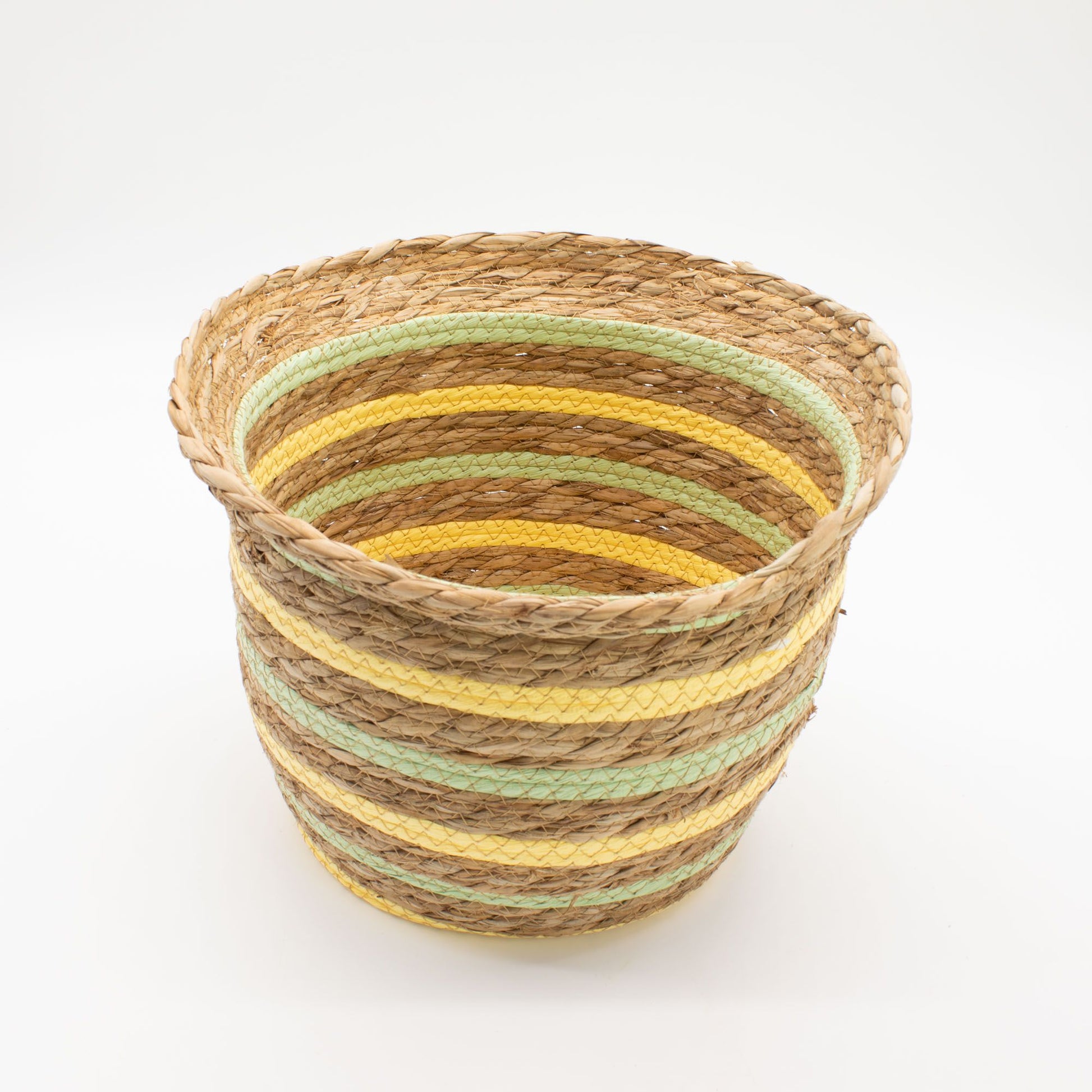 Cesta artesanal con forma de jarrón, tejida en hierba marina con rayas decorativas en tonos amarillo y verde claro.
