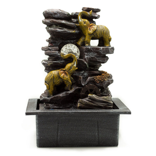 Fuente de interior: dos elefantes dorados en rocas oscuras, bola de cristal iluminada y pequeña rueda de agua.