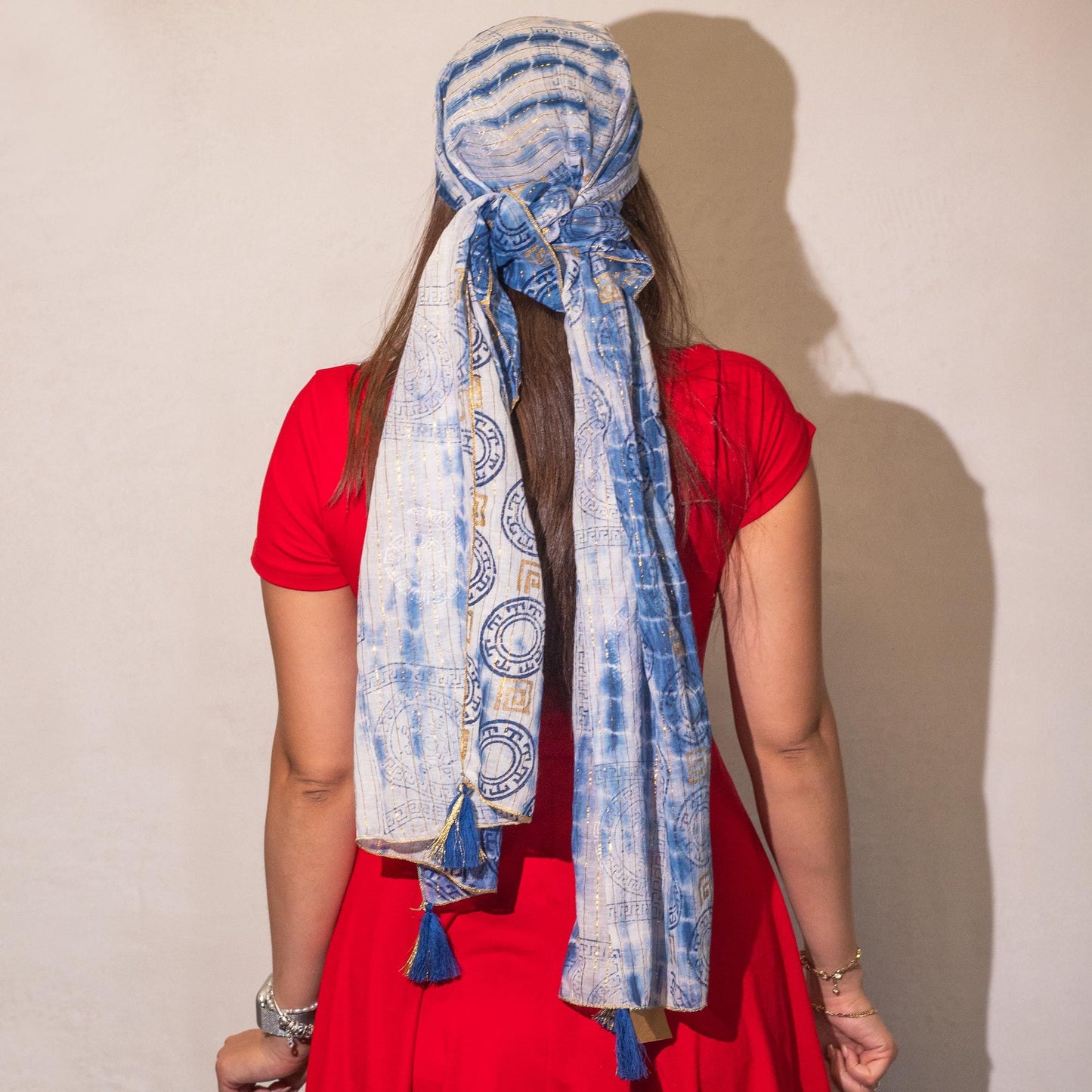 Pañuelo azul de algodón con estampado tribal, ideal como accesorio de moda, atado con flecos en un vestido rojo.