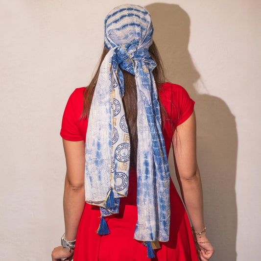 Pañuelo azul de algodón con estampado tribal, ideal como accesorio de moda, atado con flecos en un vestido rojo.