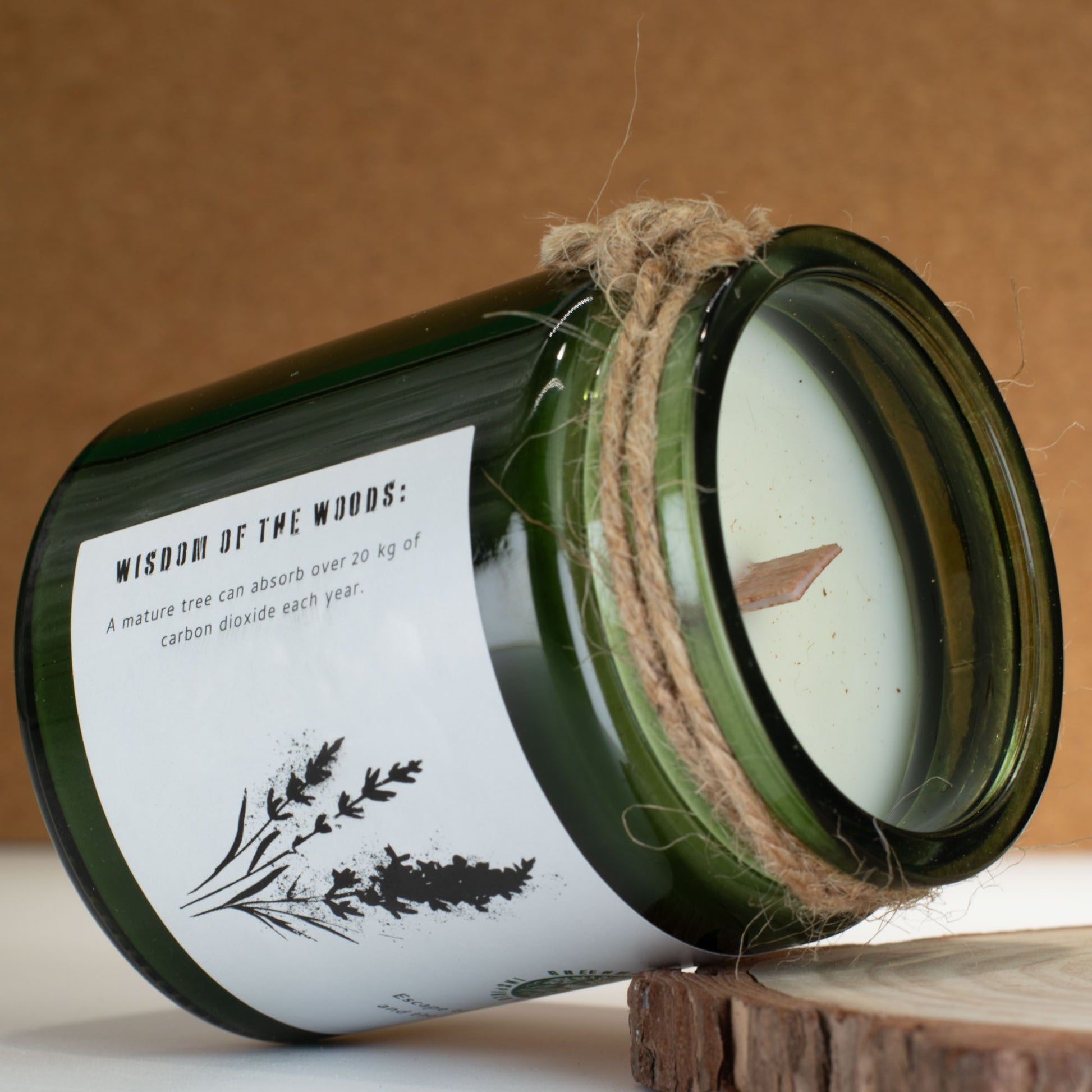 Vela verde en recipiente de vidrio con etiqueta, perfumada a madera y con cuerda decorativa. Ideal para decoración.