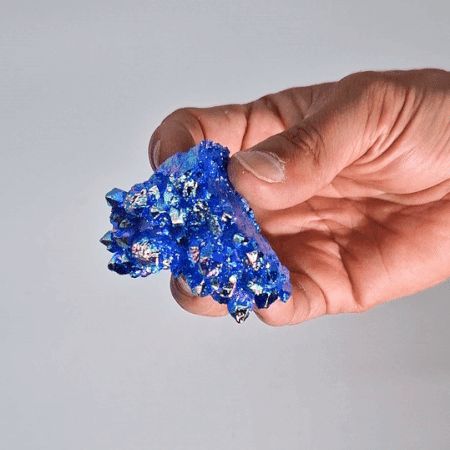 Cristal azul brillante en mano, con chispas metálicas y textura rugosa, ideal para decoración o colección.