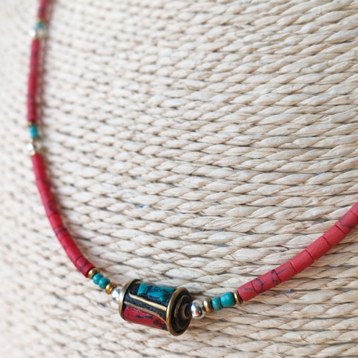 Collar de cuentas rojas y turquesas, con detalle de plata, estilo bohemio y materiales naturales.