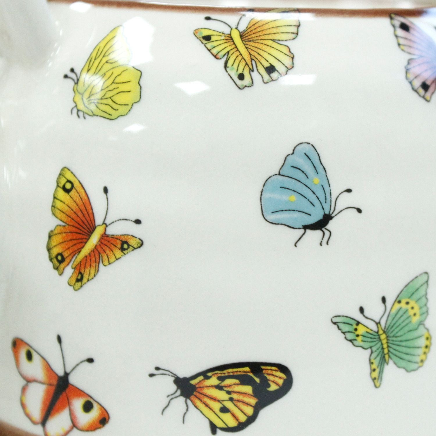Taza de cerámica blanca con mariposas de colores brillantes: amarillas, naranjas, azules y verdes.