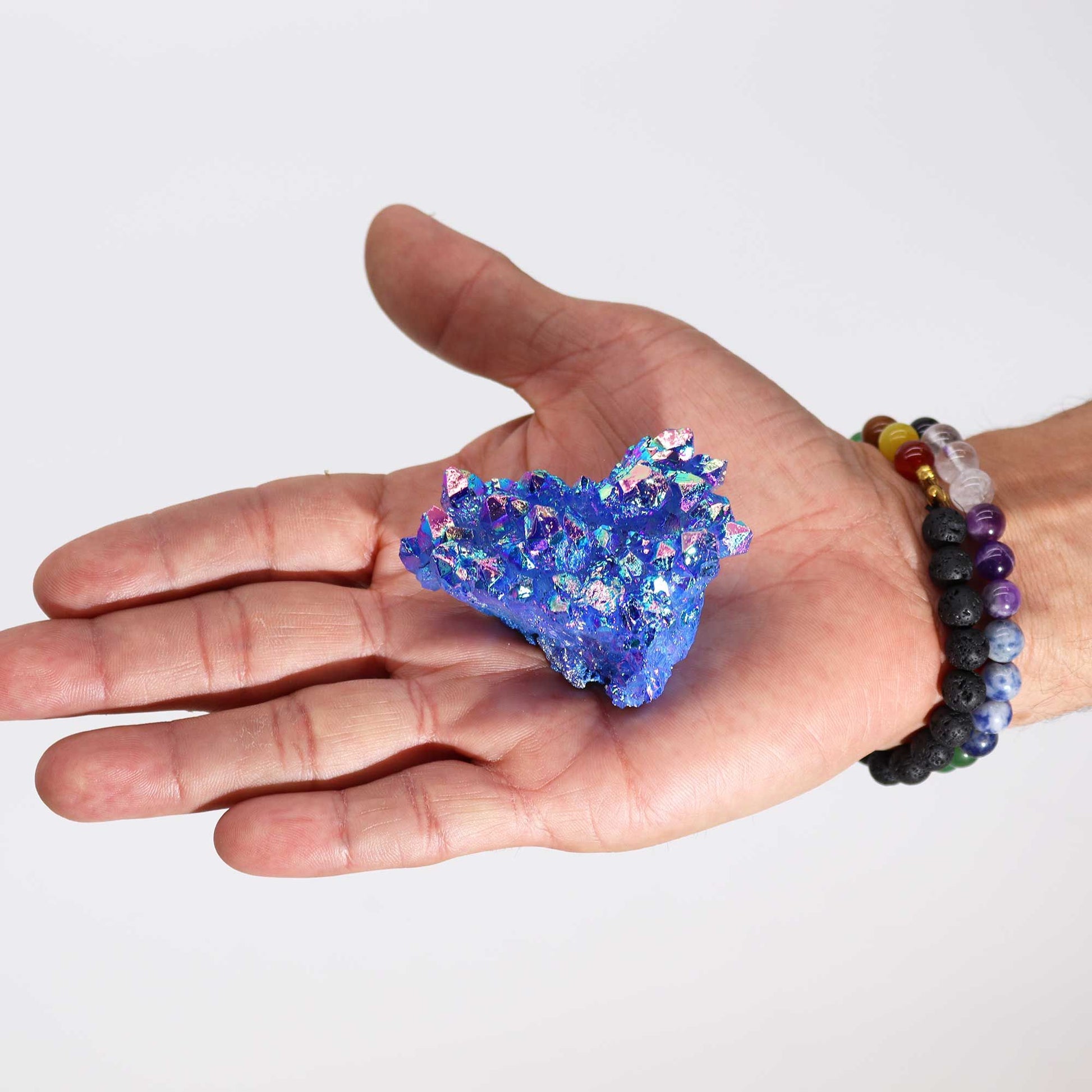 Cristal brillante azul con destellos iridiscentes, sostenido en una mano, ideal para decoración y colección.