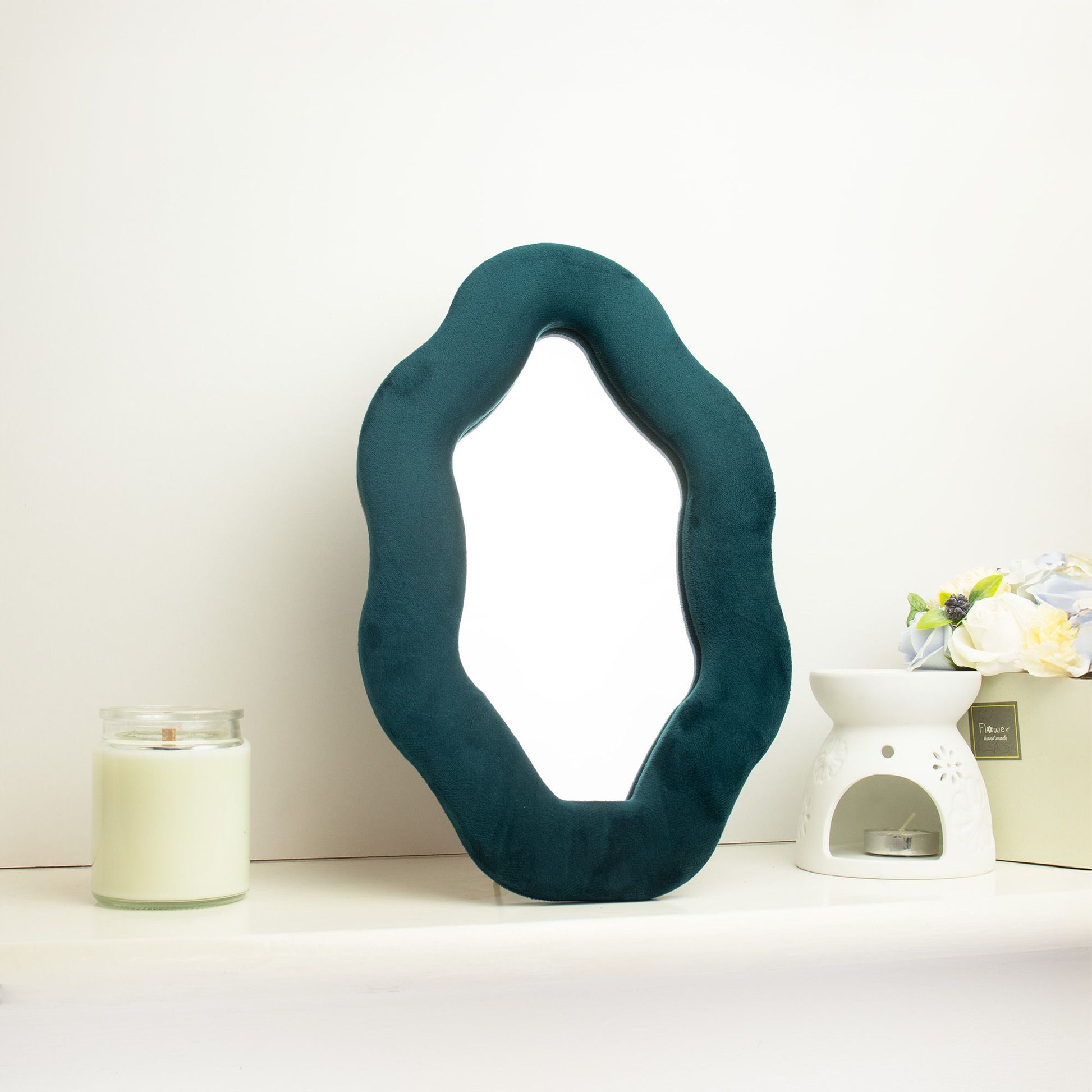 Espejo decorativo verde esmeralda con forma orgánica y borde de terciopelo, ideal para adornar espacios modernos.