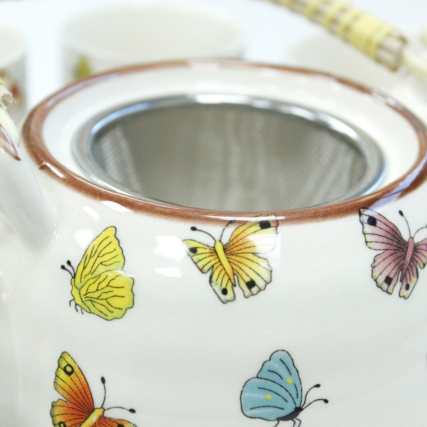 Tetera de cerámica blanca con mariposas de colores amarillas, rosas y azules, estilo vintage, tamiz de acero inoxidable.