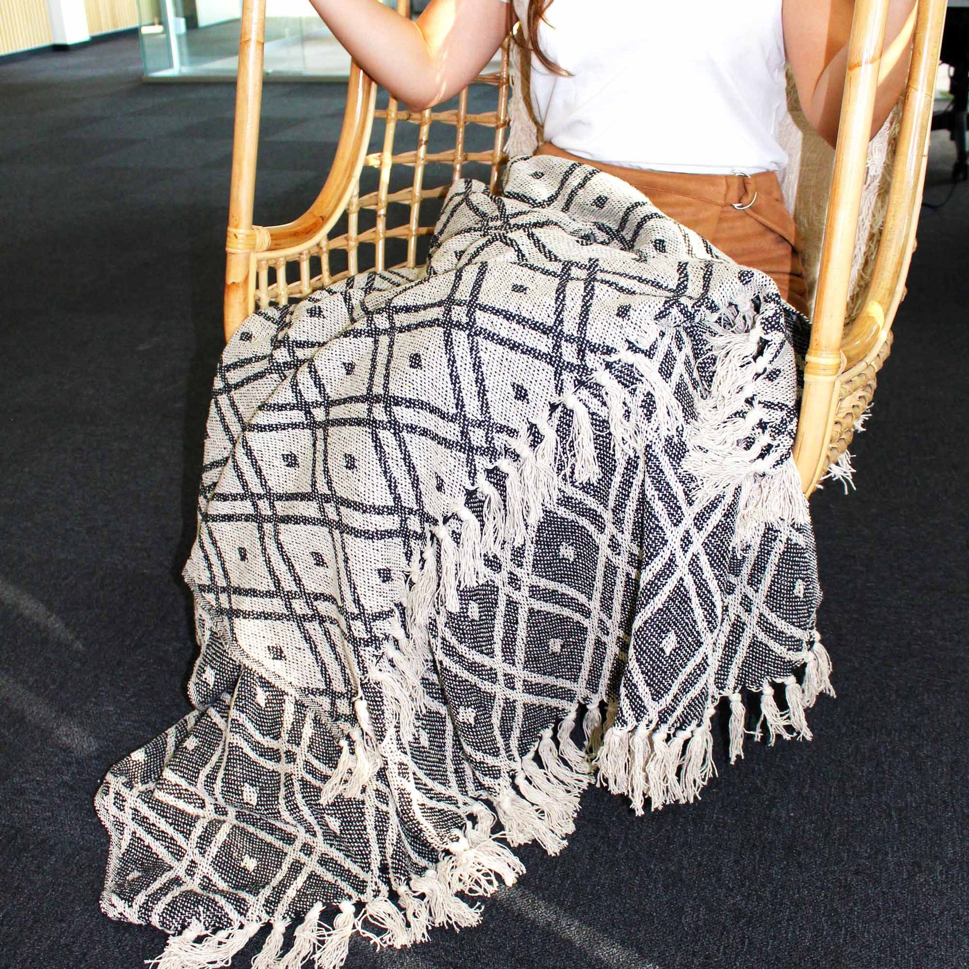 Manta tejida en negro y blanco con flecos, estilo bohemio, perfecta para decorar y abrigar.