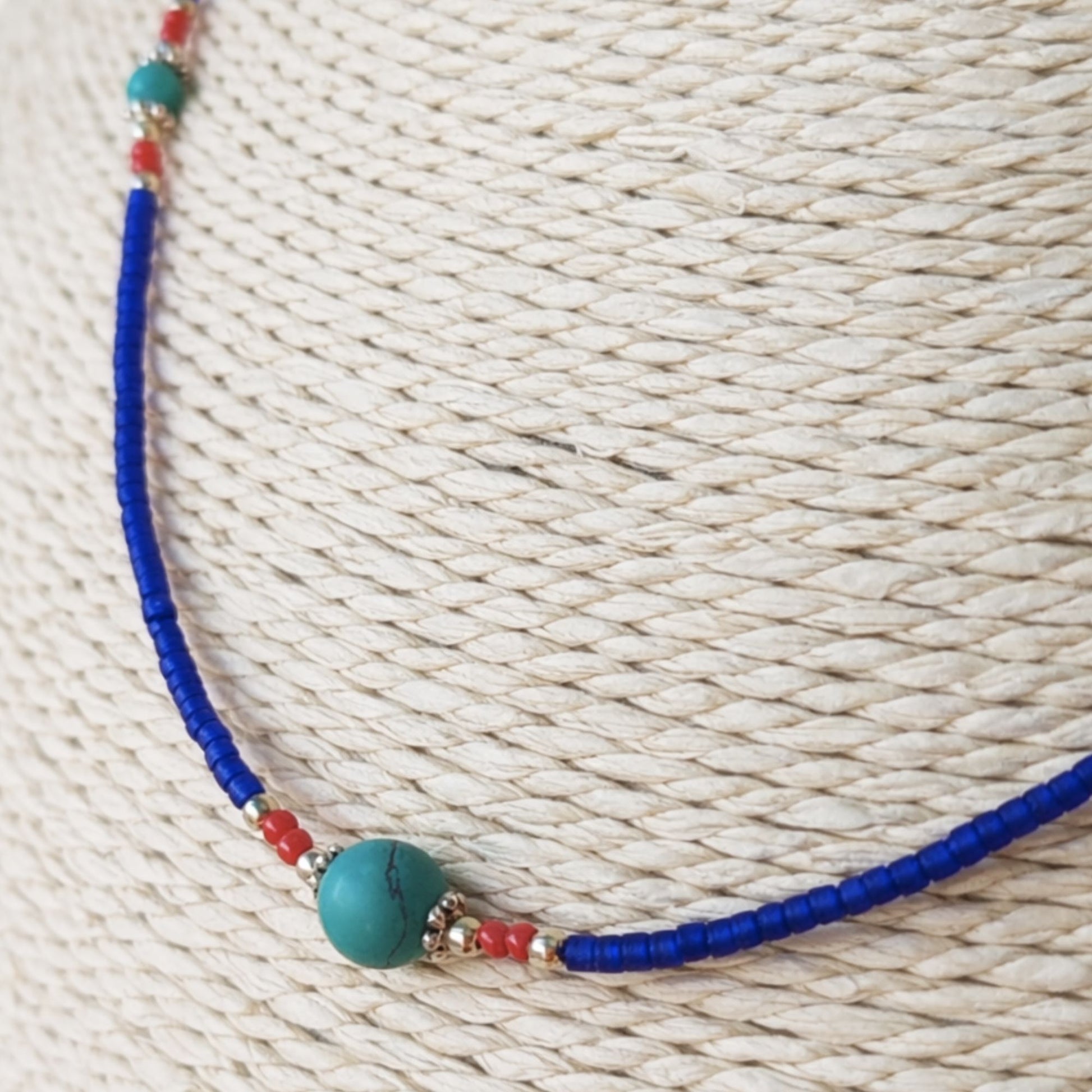 Collar de cuentas azul y roja con perla de turquesa, estilo bohemio y hecho de materiales naturales.