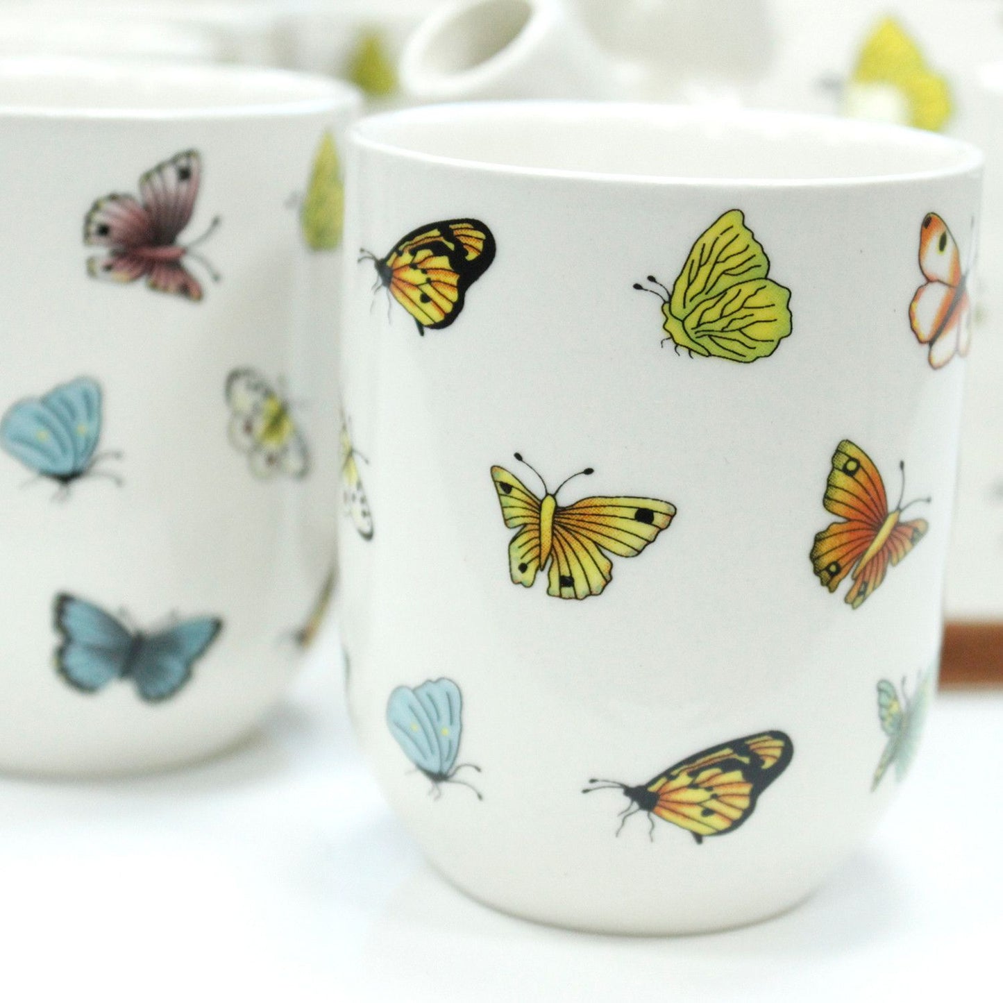 Vaso de cerámica blanco con mariposas de colores brillantes en estilo moderno. Ideal para café o té.