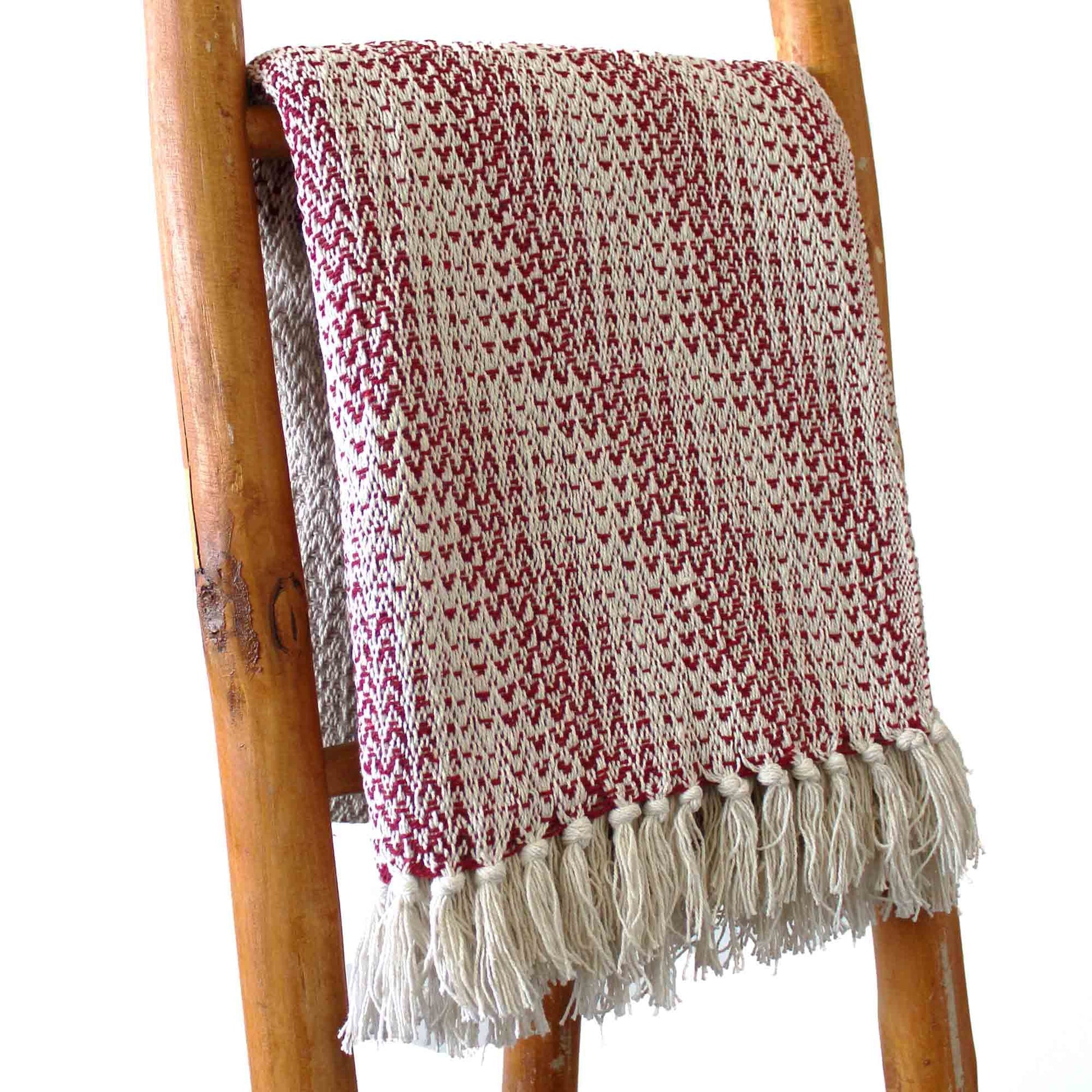 Manta de algodón en tonos rojo y crema, con diseño texturizado y flecos, perfecta para decoración acogedora.