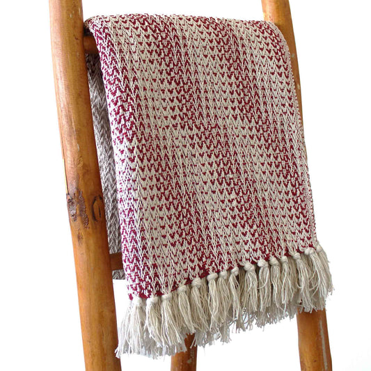 Manta de algodón en tonos rojo y crema, con diseño texturizado y flecos, perfecta para decoración acogedora.
