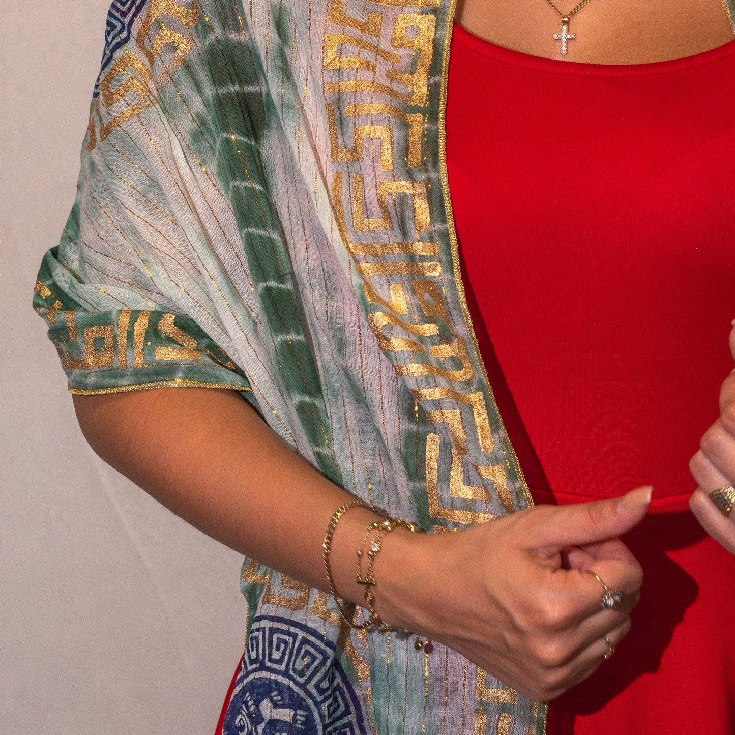 Chal color verde y dorado, estilo bohemio, sobre vestido rojo, detalles de estampado clásico y elegante.