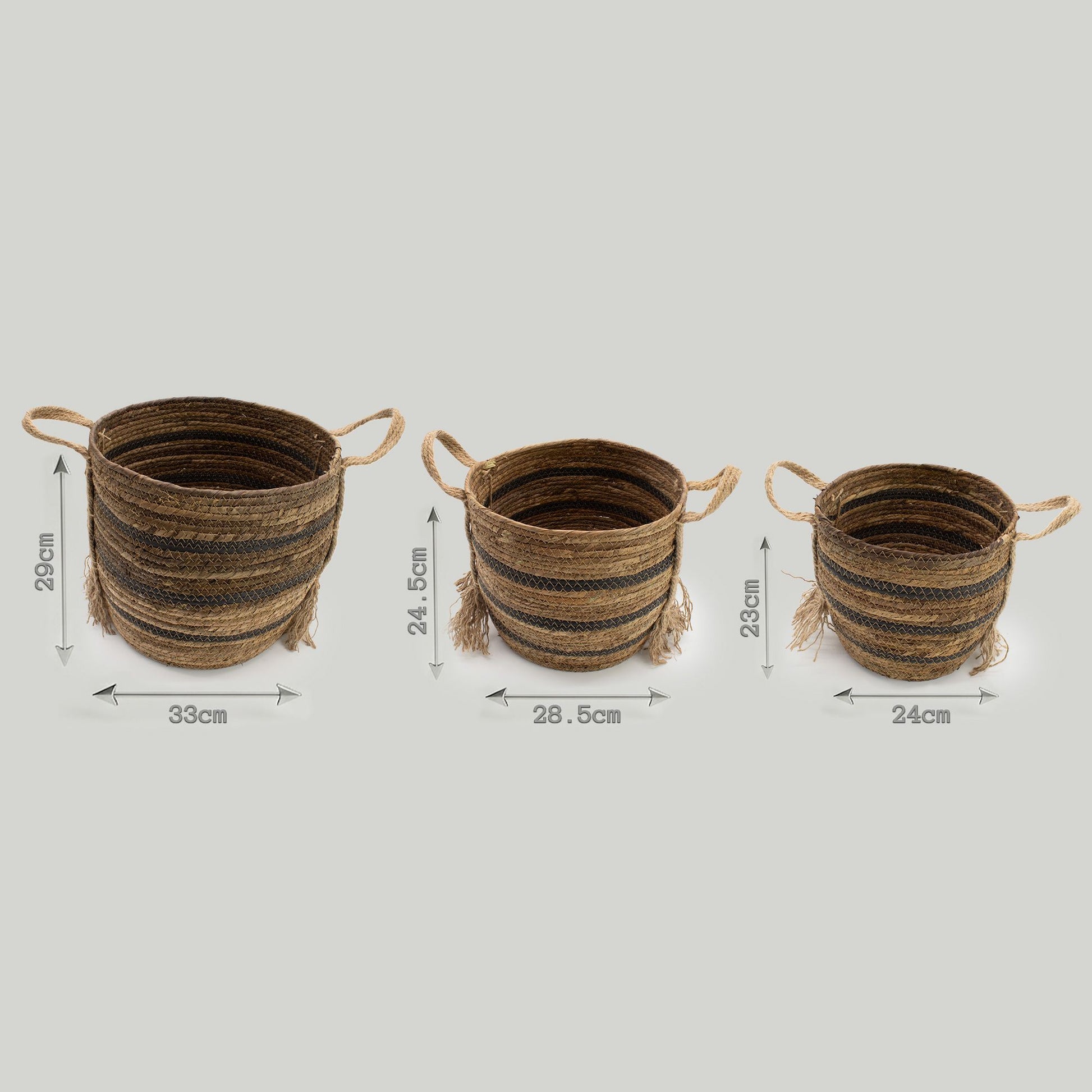 Set de 3 cestas redondas de hoja de plátano y pasto marino color marrón con asas y detalles de flecos.