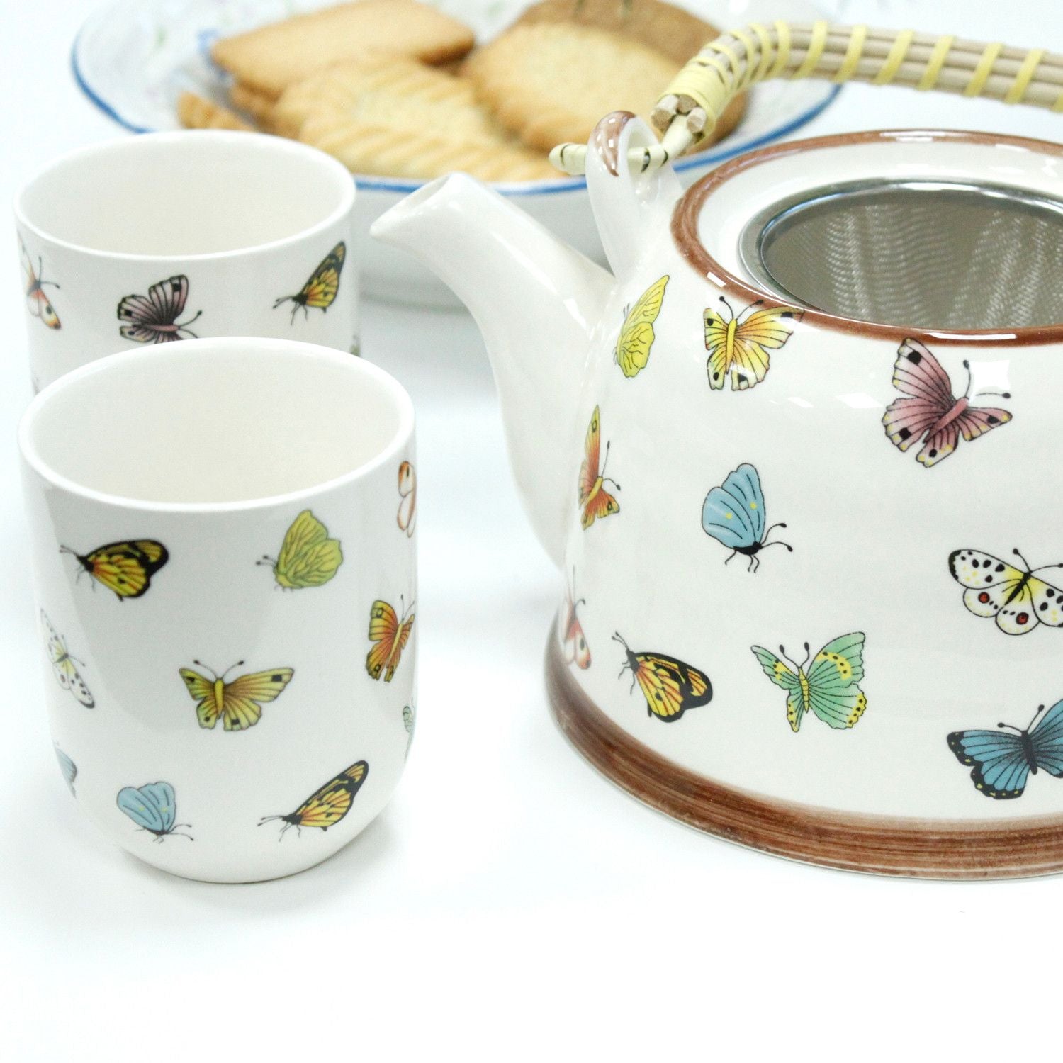 Juego de té blanco con mariposas de colores, incluye tetera y dos tazas de cerámica.