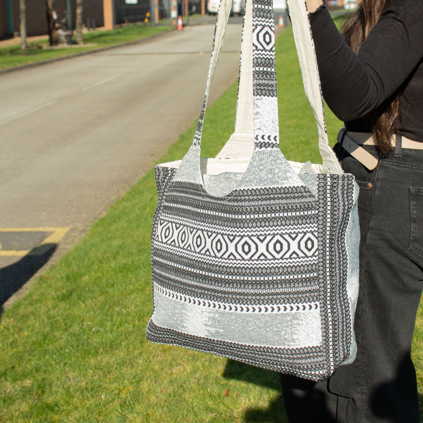 Bolso de mano grande en tonos gris y blanco, con diseño étnico y asas de tela resistentes. Ideal para uso diario.