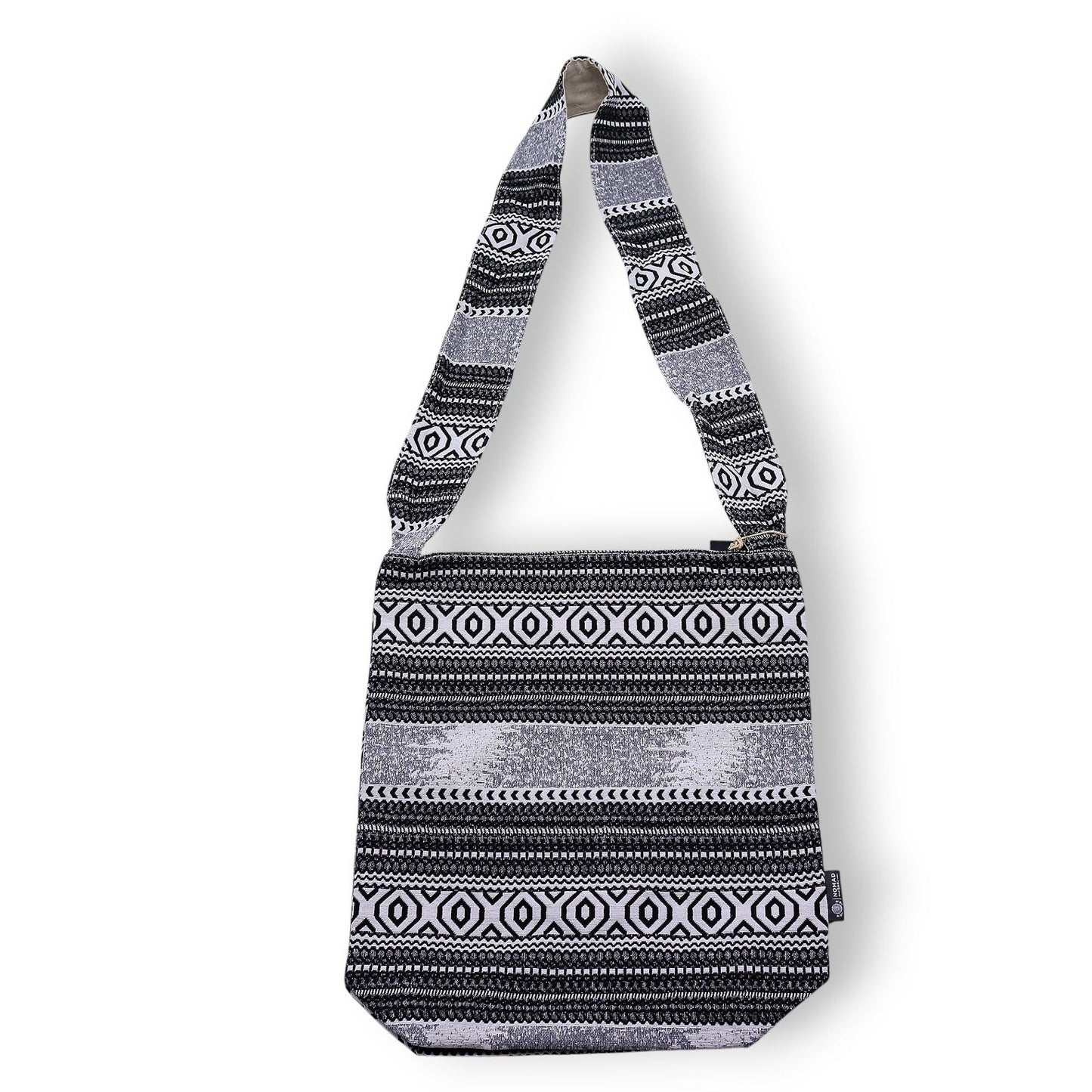 Bolso negro y blanco con diseño étnico, confeccionado en material textil y strap largo para cruzar.
