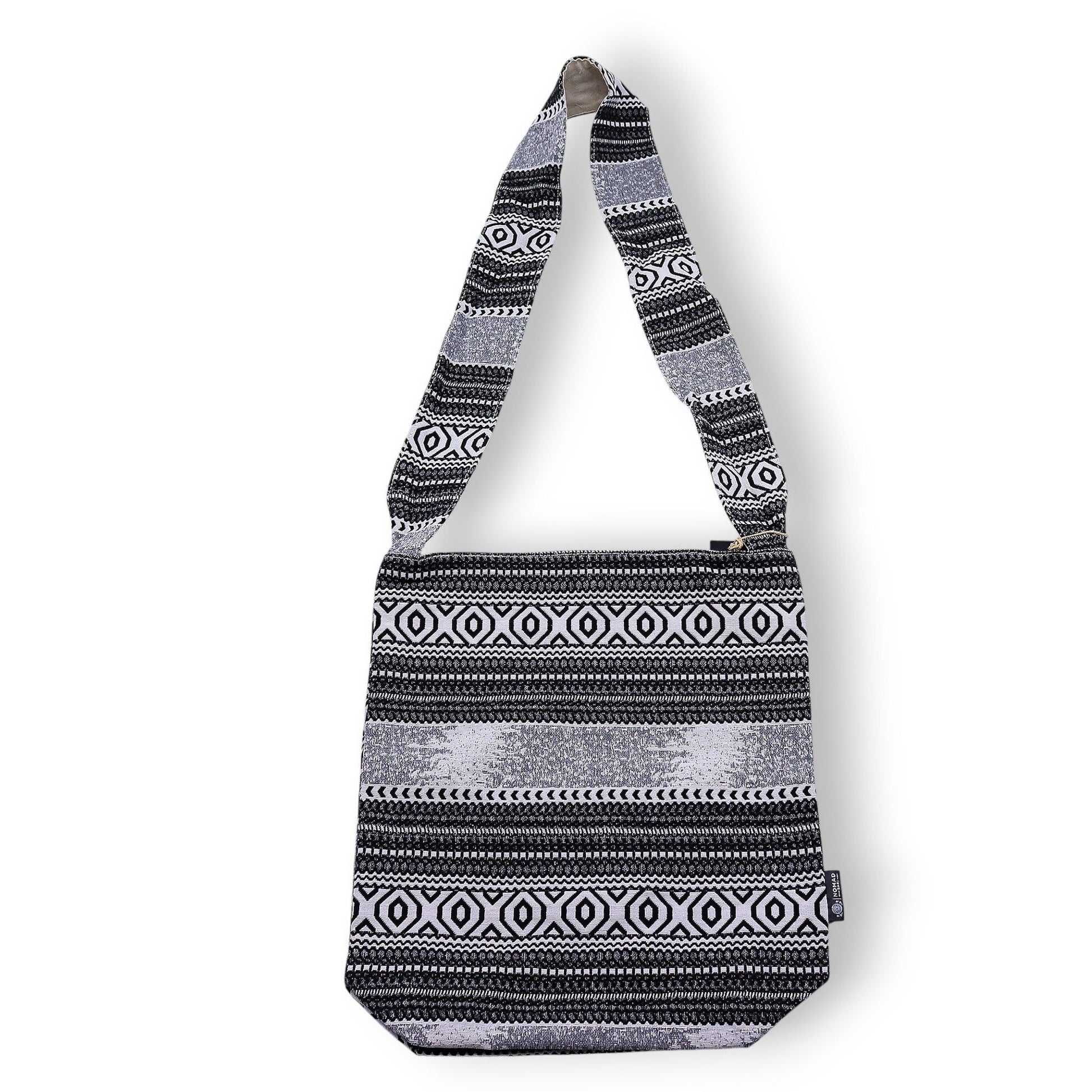 Bolso negro y blanco con diseño étnico, confeccionado en material textil y strap largo para cruzar.