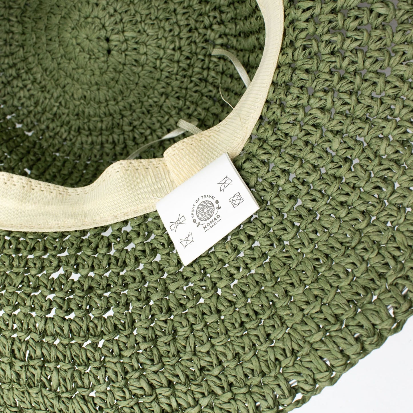 Sombrero de paja trenzada verde olivo, con etiqueta de marca, ideal para el verano y actividades al aire libre.