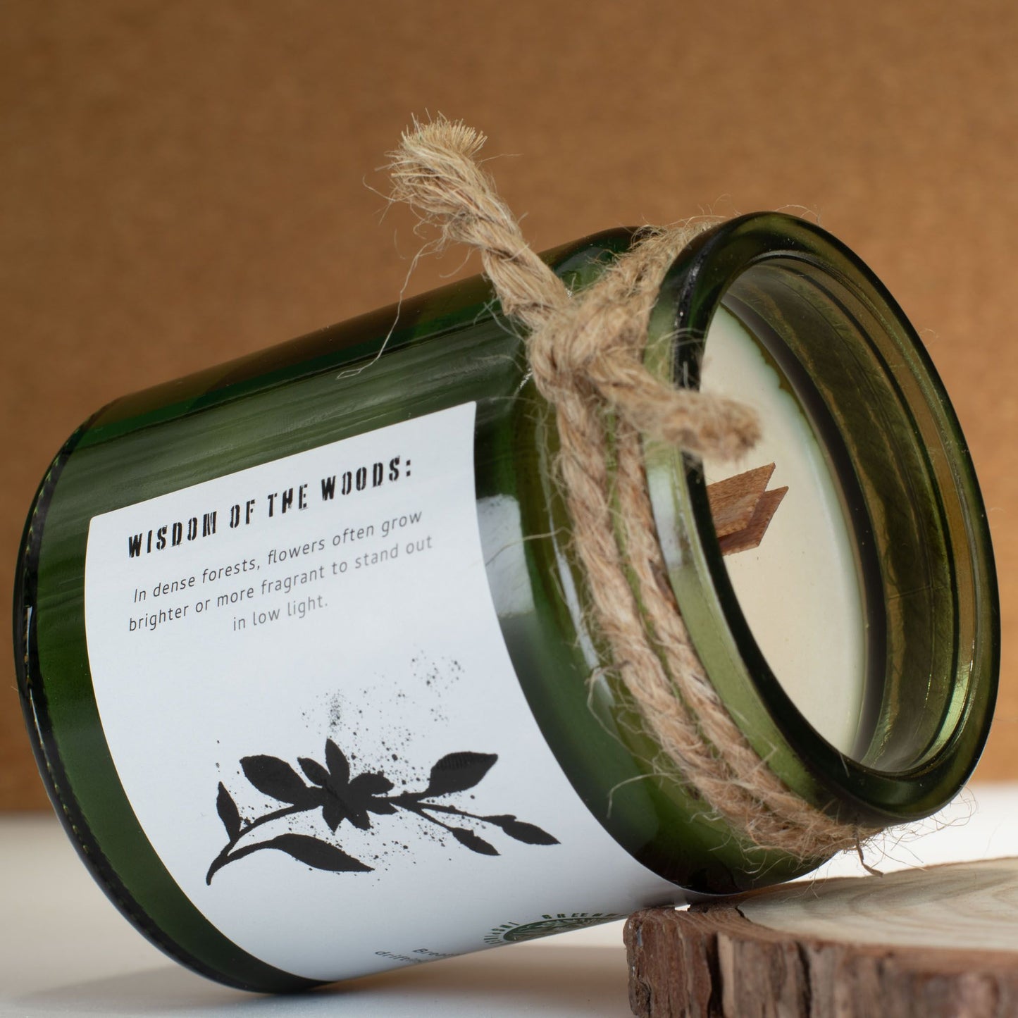 Vela verde de madera "Wisdom of the Woods" con etiqueta, decoración rústica y fragancia floral.