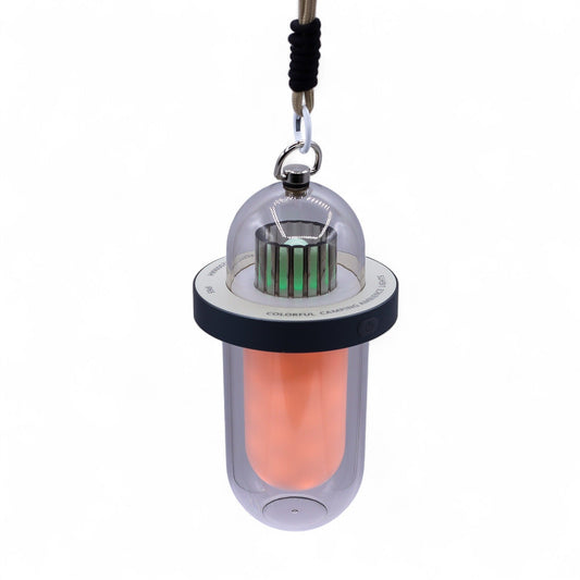 Lámpara colgante de exterior tipo cápsula con luz naranja, detalle LED verde y cordón para colgar, fondo blanco.