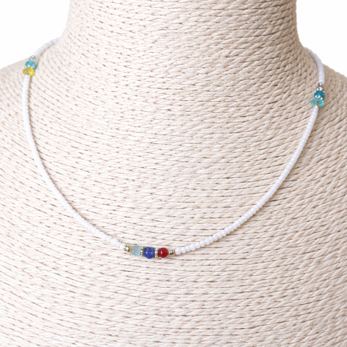 Collar de cuentas blancas con detalles en azul, rojo y verde, un estilo fresco y colorido.