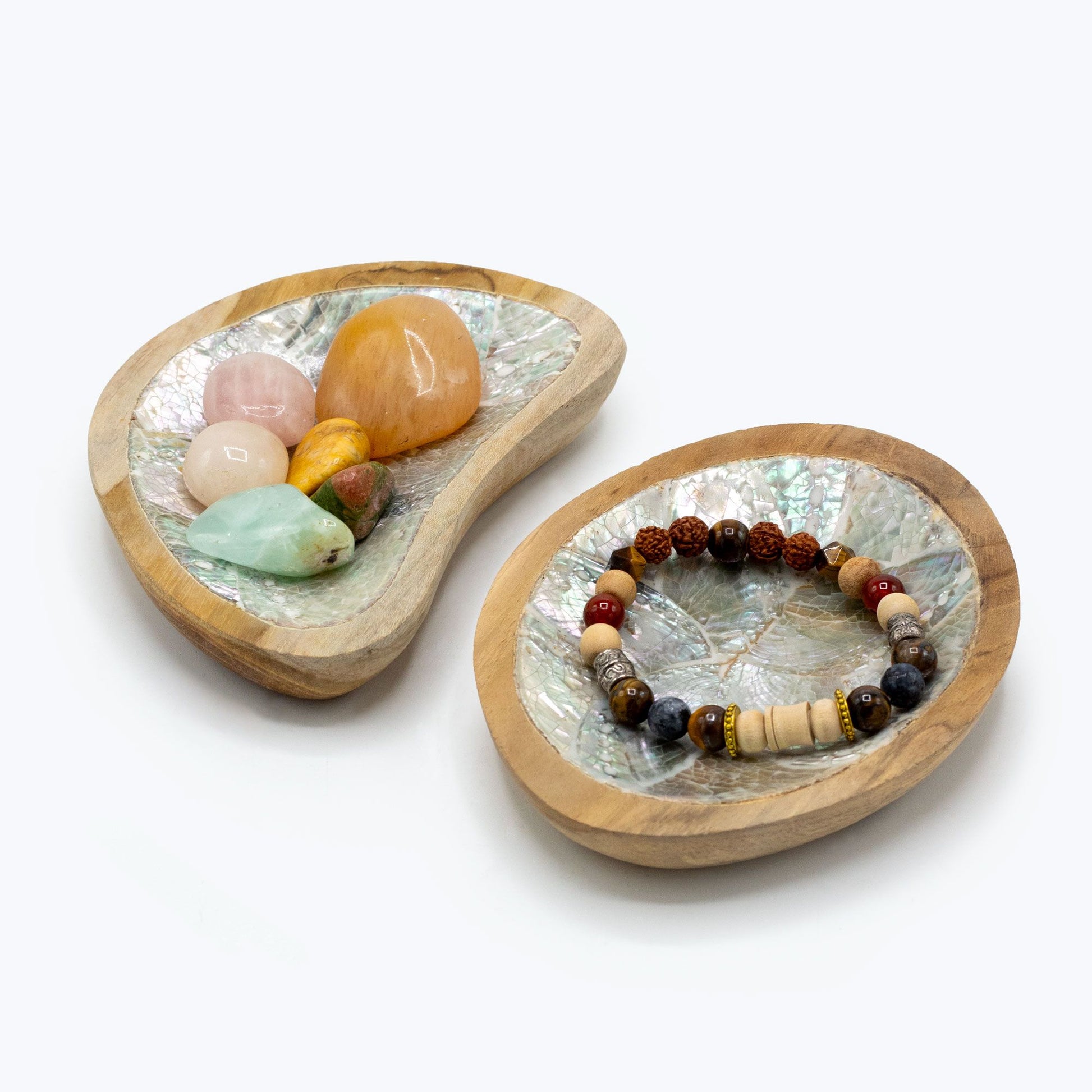 Dos cuencos de madera en forma de hoja con piedras naturales y una pulsera de cuentas de colores.