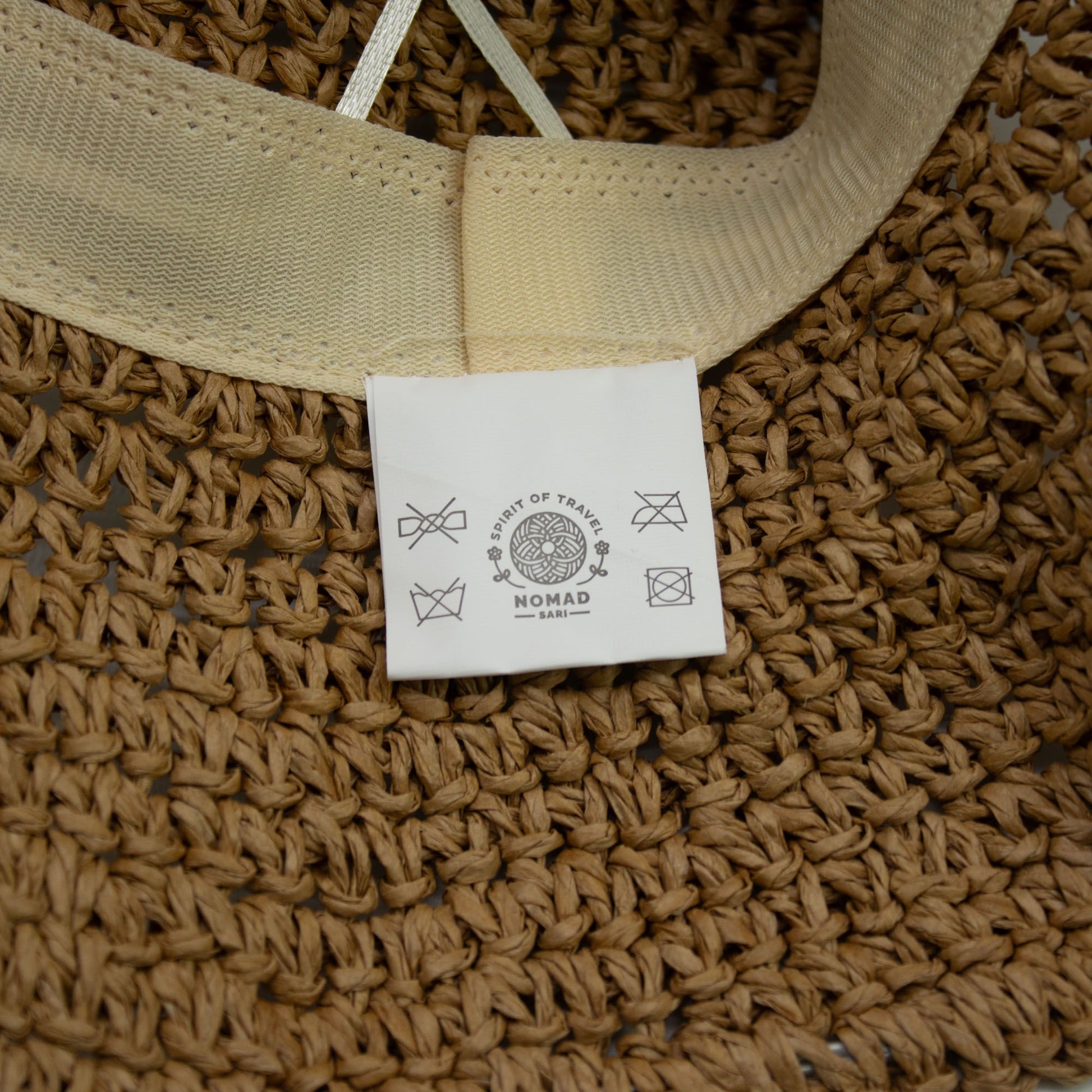 Gorro de paja trenzada color natural con cinta beige, estilo bohemio, ideal para días soleados.