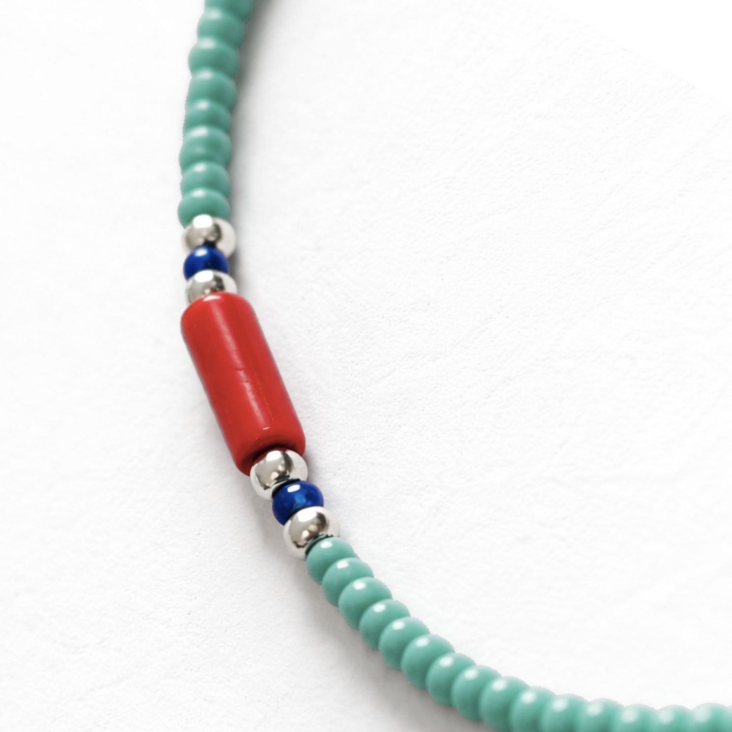 Collar de cuentas verde turquesa con detalles rojos y azules, material acrílico y diseño bohemio.