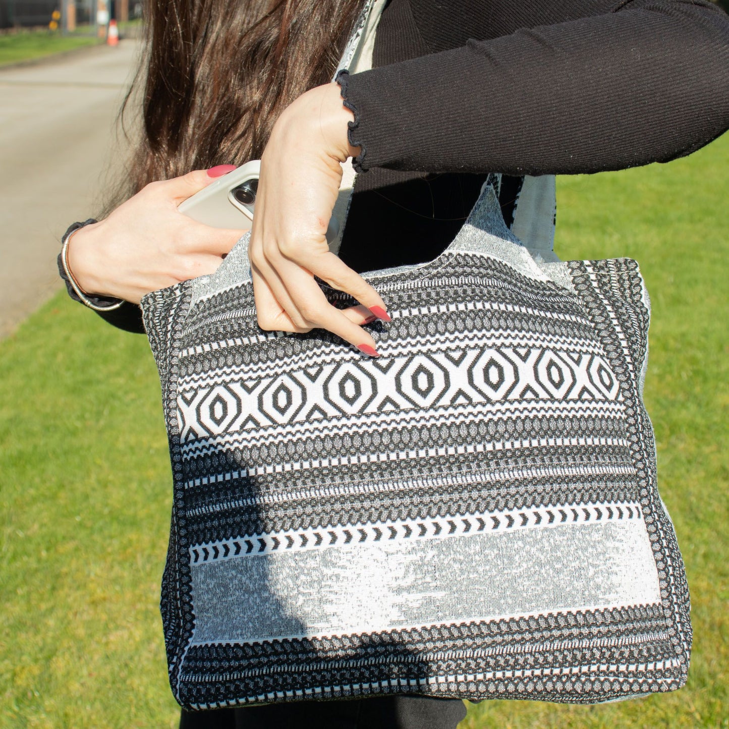 Bolso de mano negro y blanco, tejido con diseño geométrico, ideal para uso diario y estilo casual.