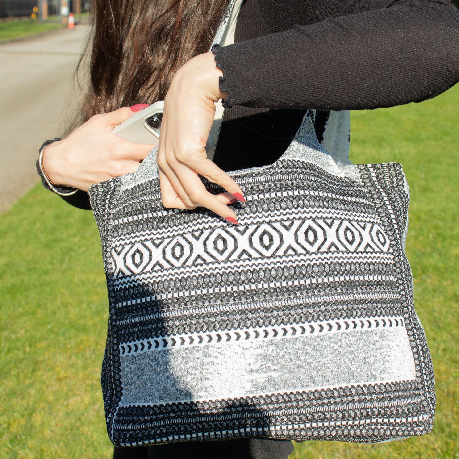Bolso de mano negro y blanco, tejido con diseño geométrico, ideal para uso diario y estilo casual.