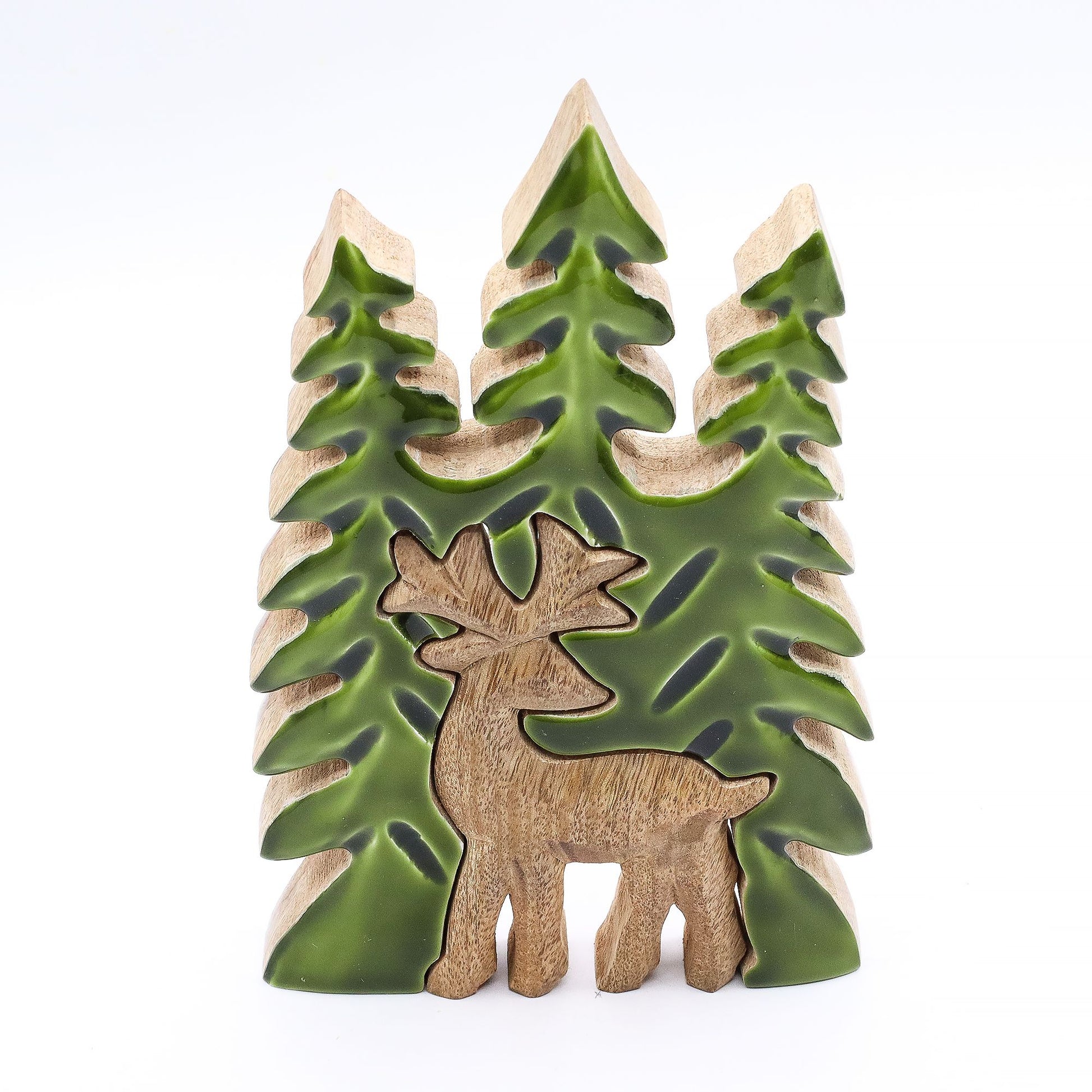 Figurita decorativa de ciervo en madera clara con verde, rodeada de pinos tallados, estilo rústico moderno.