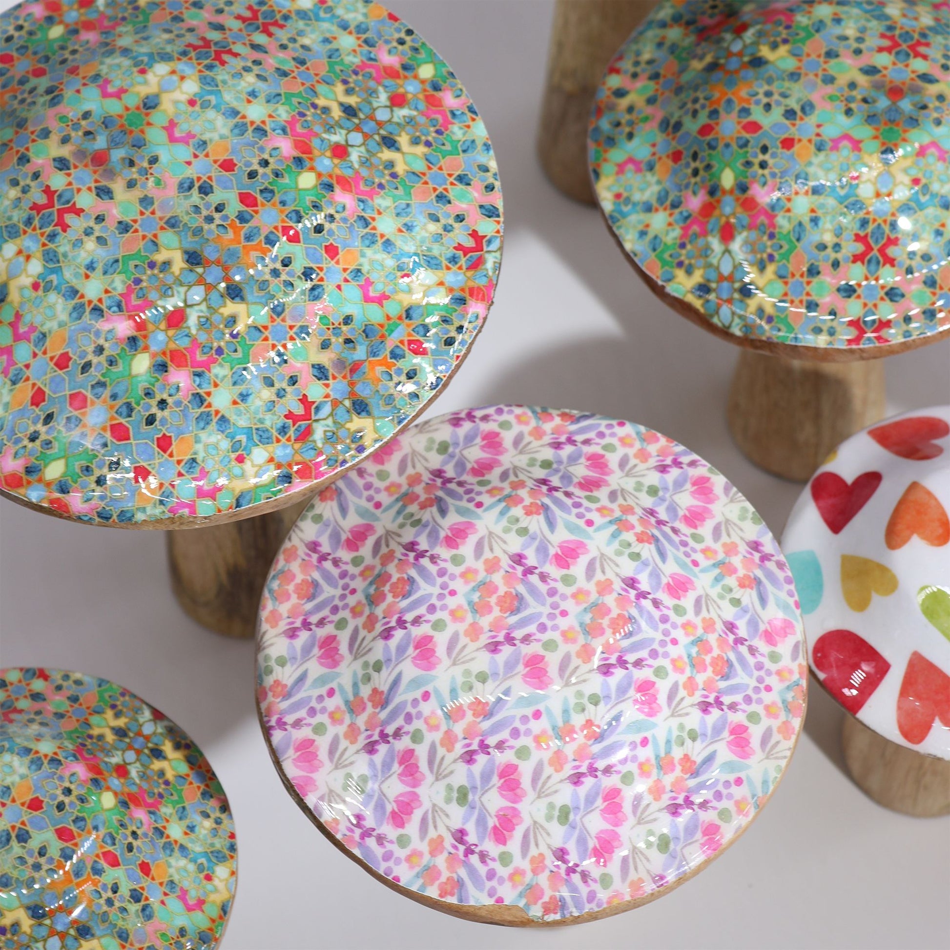 Conjunto de setas decorativas de cerámica colorida con estampados florales y geométricos sobre base de madera.