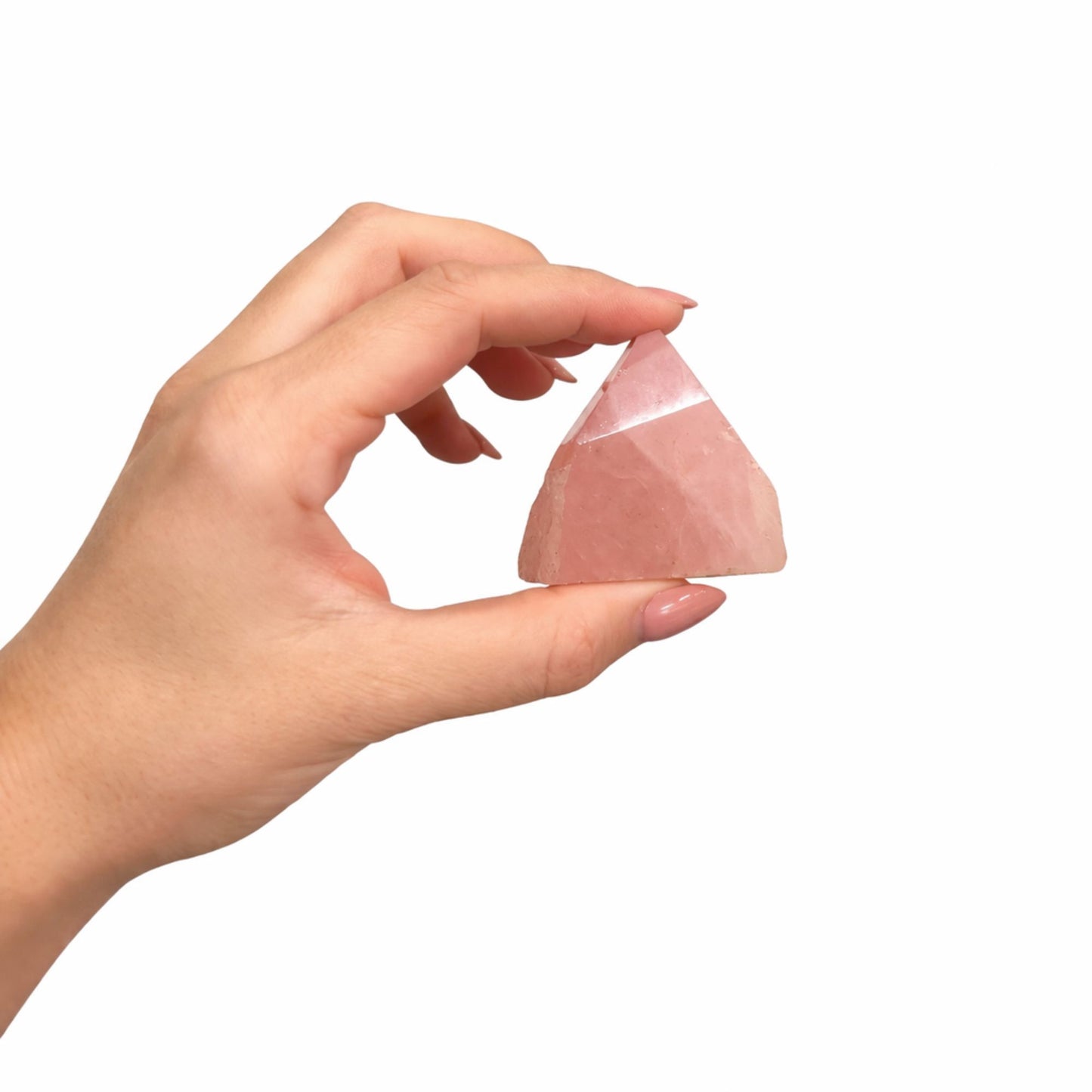 Piedra de cuarzo rosa en forma de pirámide, sostenida a mano, para decoración o meditación.