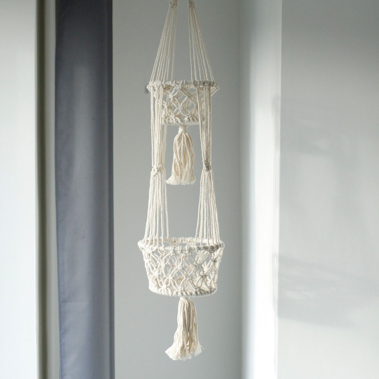 Macramé colgante en color crema con dos cestas decorativas y flecos, ideal para plantas y decoración boho.