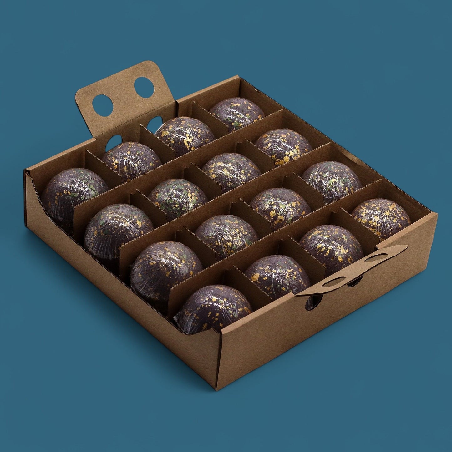 Caja de 15 bombas de baño de chocolate negro decorados con dorado, en envase de cartón reciclable.