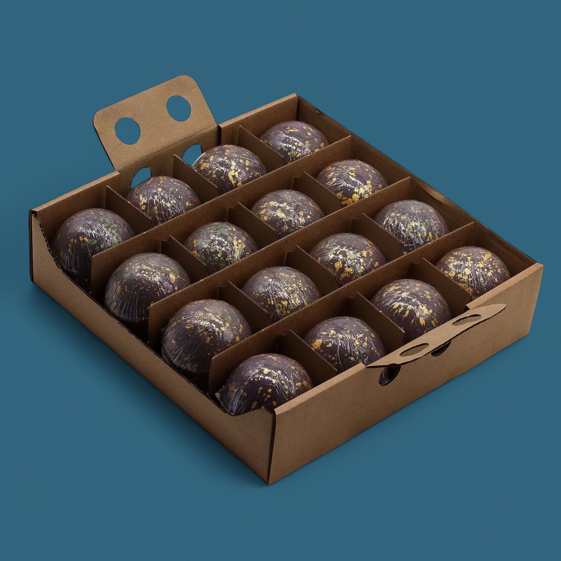 Caja de 15 bombas de baño de chocolate negro decorados con dorado, en envase de cartón reciclable.