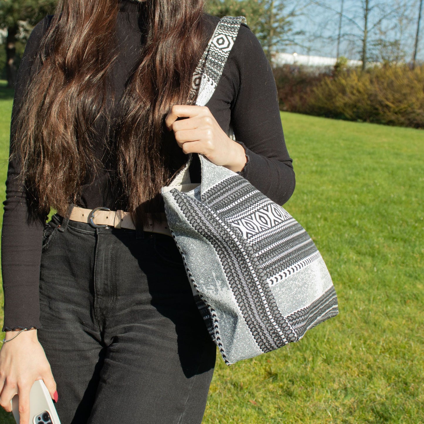 Bolso de mano negro y plateado con diseño étnico, fabricado en tejido resistente y elegante, ideal para cualquier ocasión.