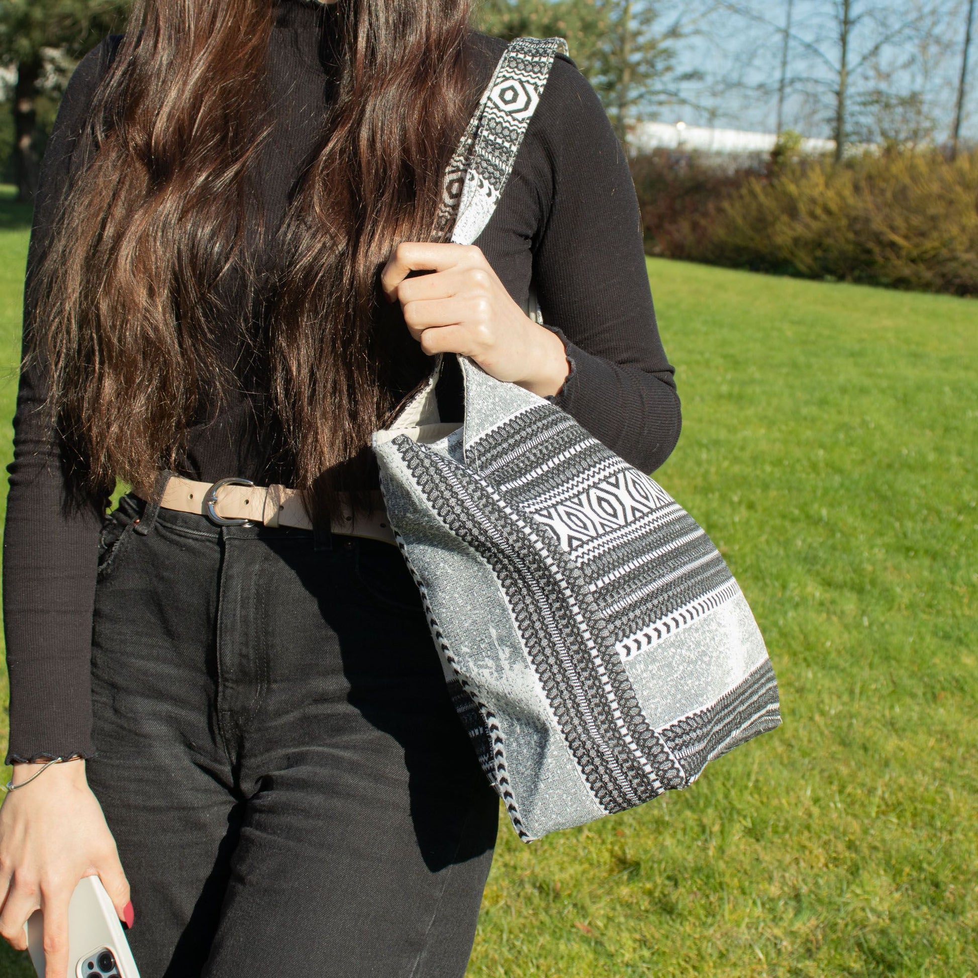 Bolso de mano negro y plateado con diseño étnico, fabricado en tejido resistente y elegante, ideal para cualquier ocasión.