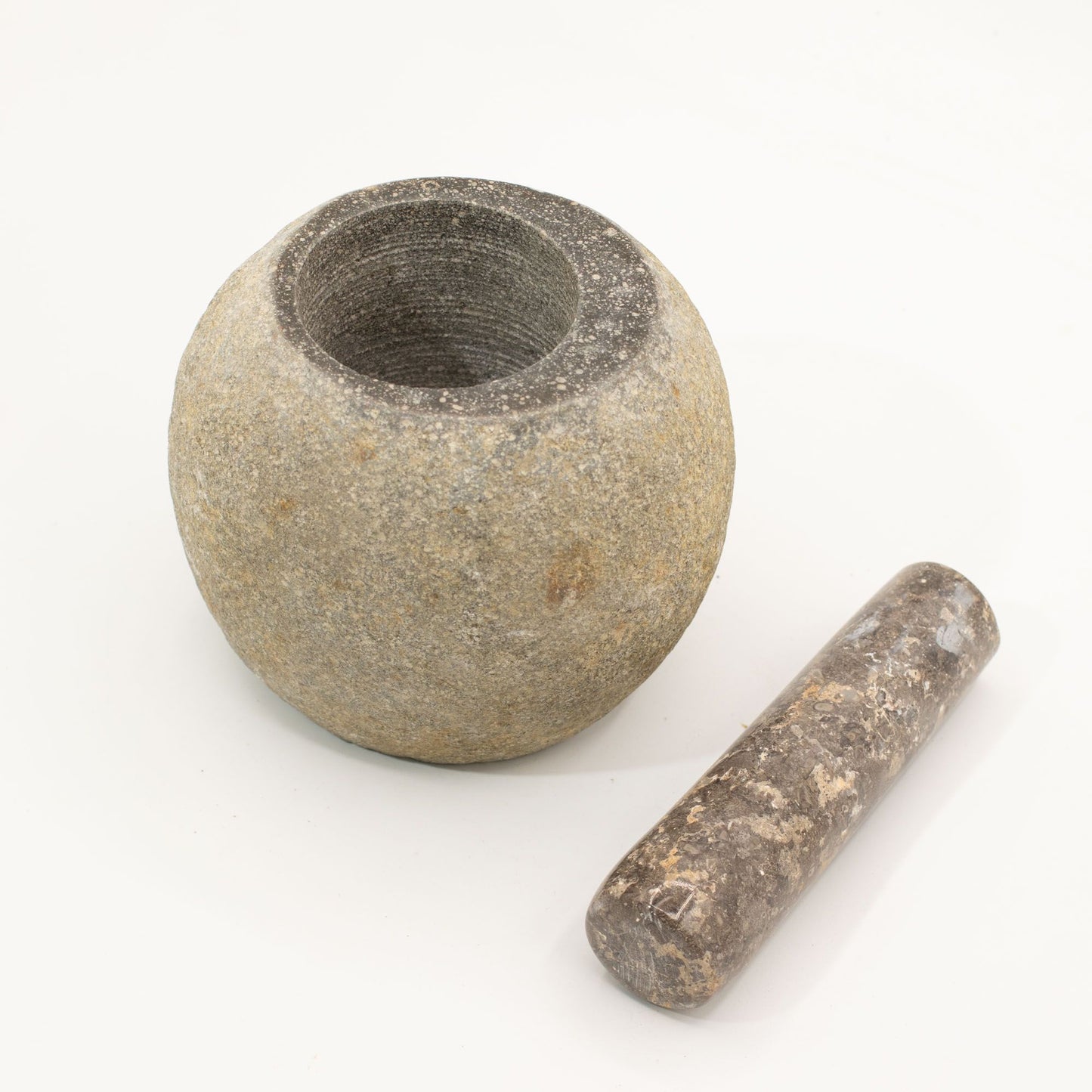 Mortero de piedra gris con mano de piedra chocolate, estilo rústico y natural, ideal para cocina gourmet.