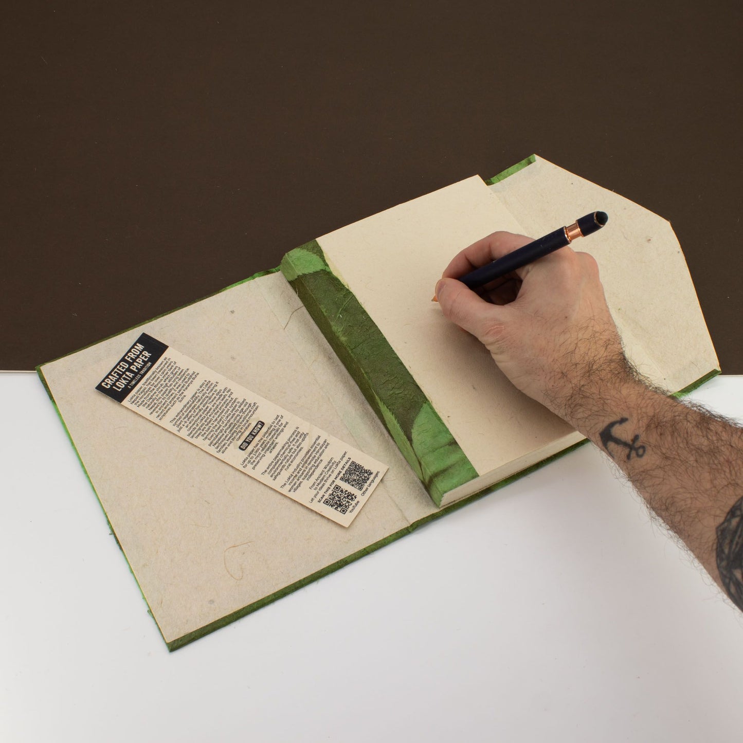 Cuaderno artesanal con cubiertas verdes y hojas en blanco, ideal para escritura creativa y dibujo.