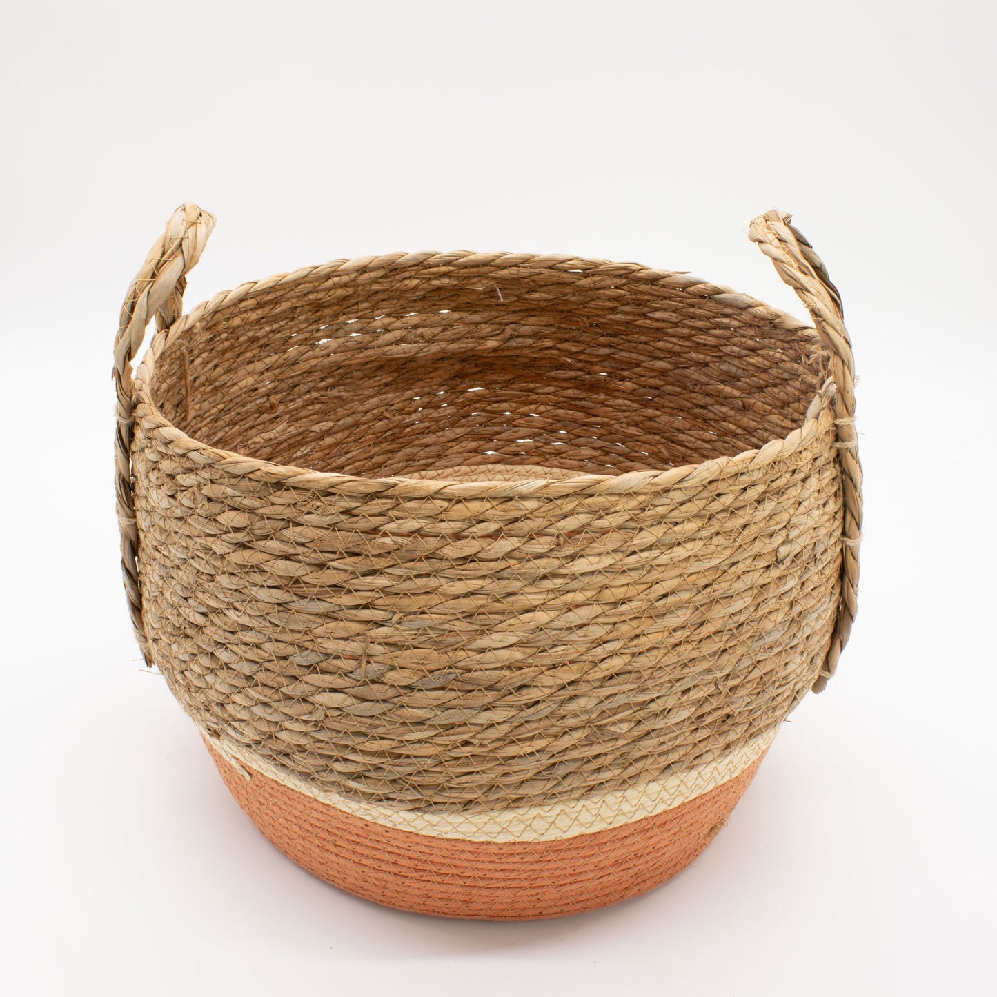 Cesta redonda de fibra natural y pasto marino con base de color naranja y dos asas laterales sobre fondo blanco.