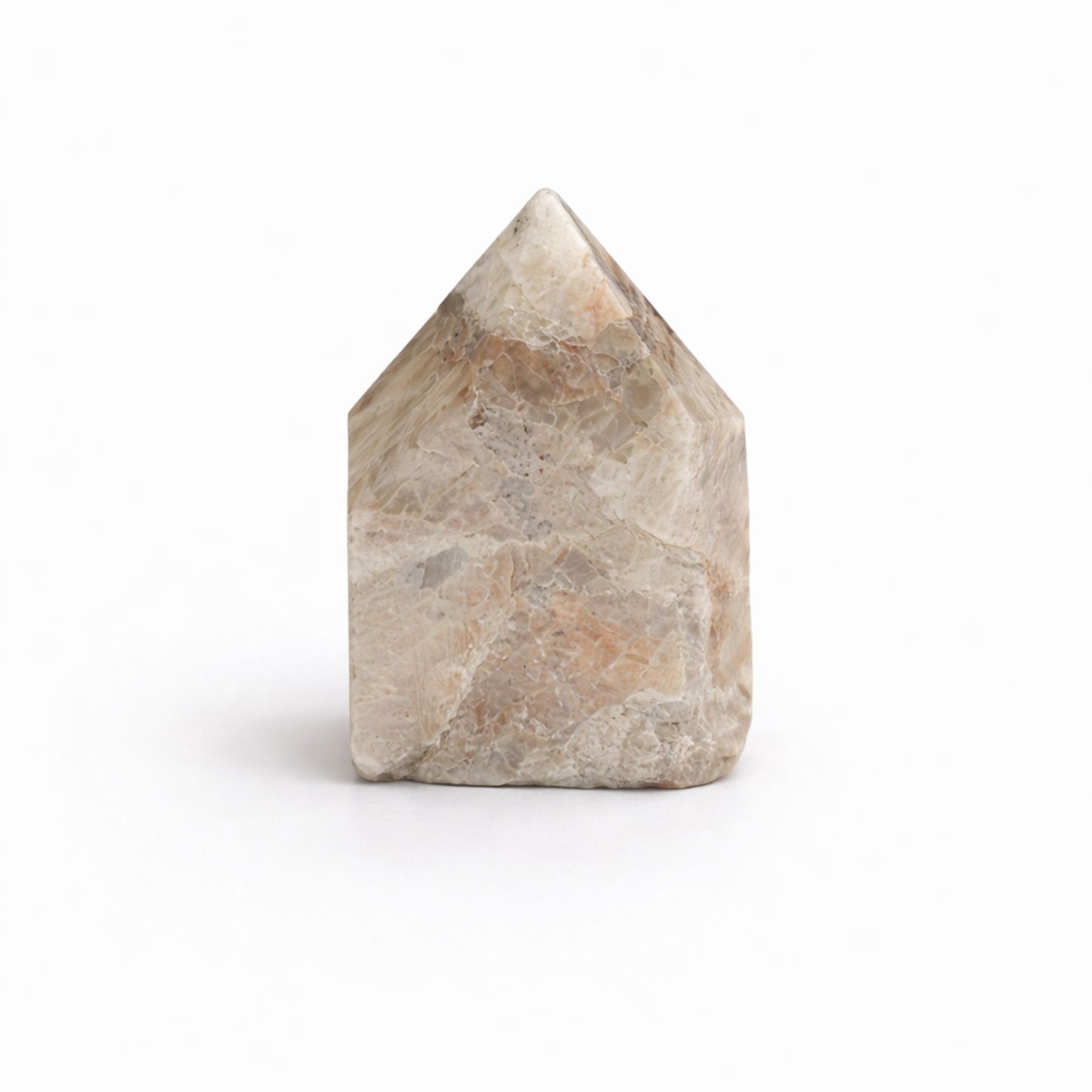 Piedra mineral en forma de casa, tonos beige y gris, superficie pulida, ideal para decoración y prácticas espirituales.
