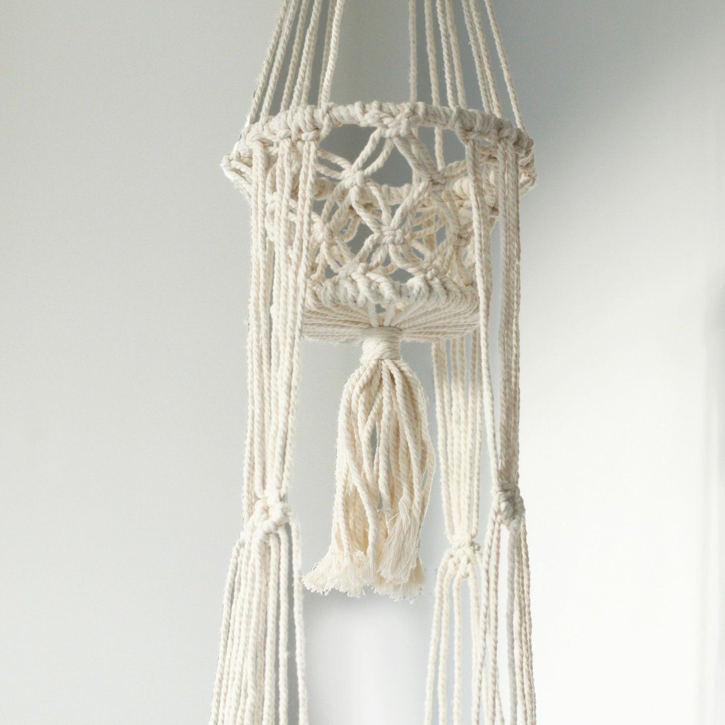 Macramé blanco colgante para plantas, tejido en algodón, estilo bohemio con borlas decorativas.