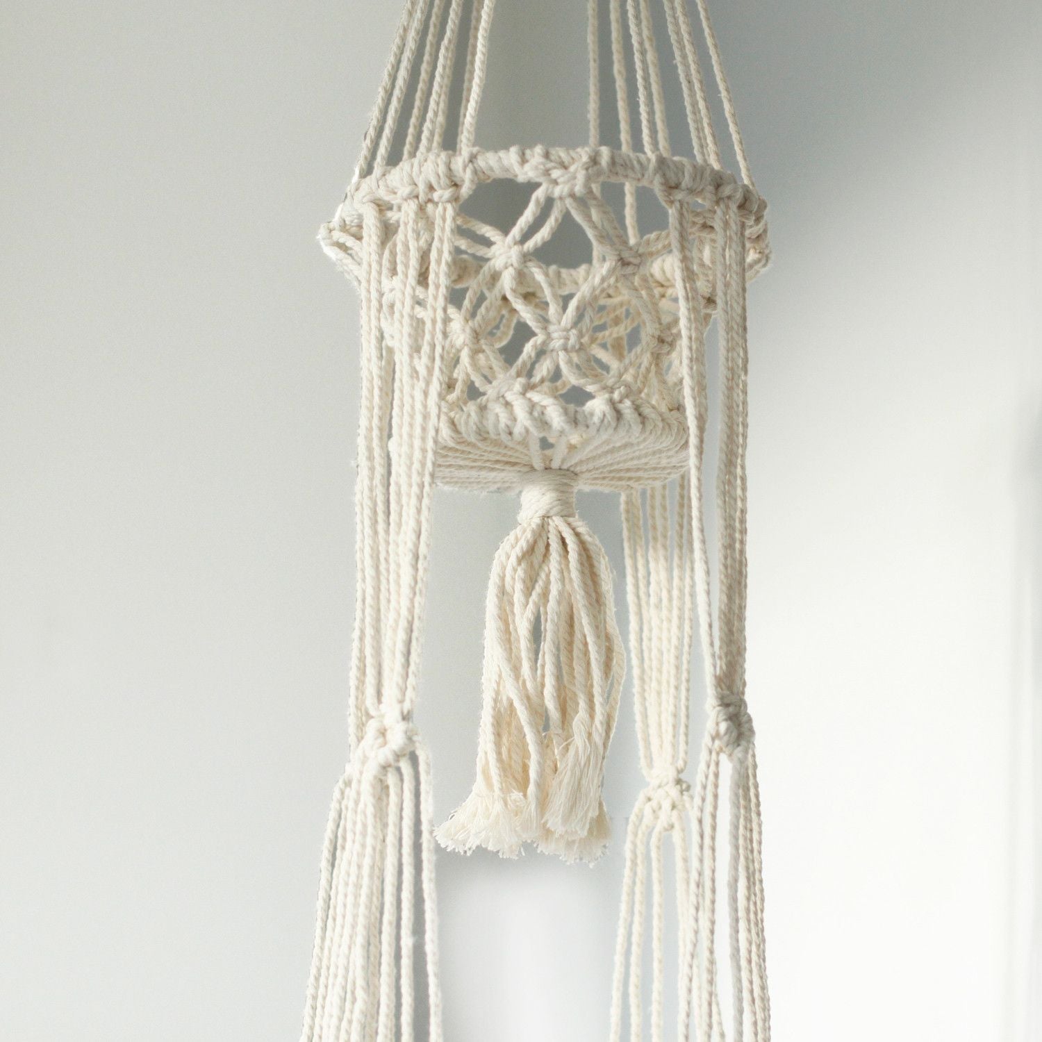 Macramé blanco colgante para plantas, tejido en algodón, estilo bohemio con borlas decorativas.