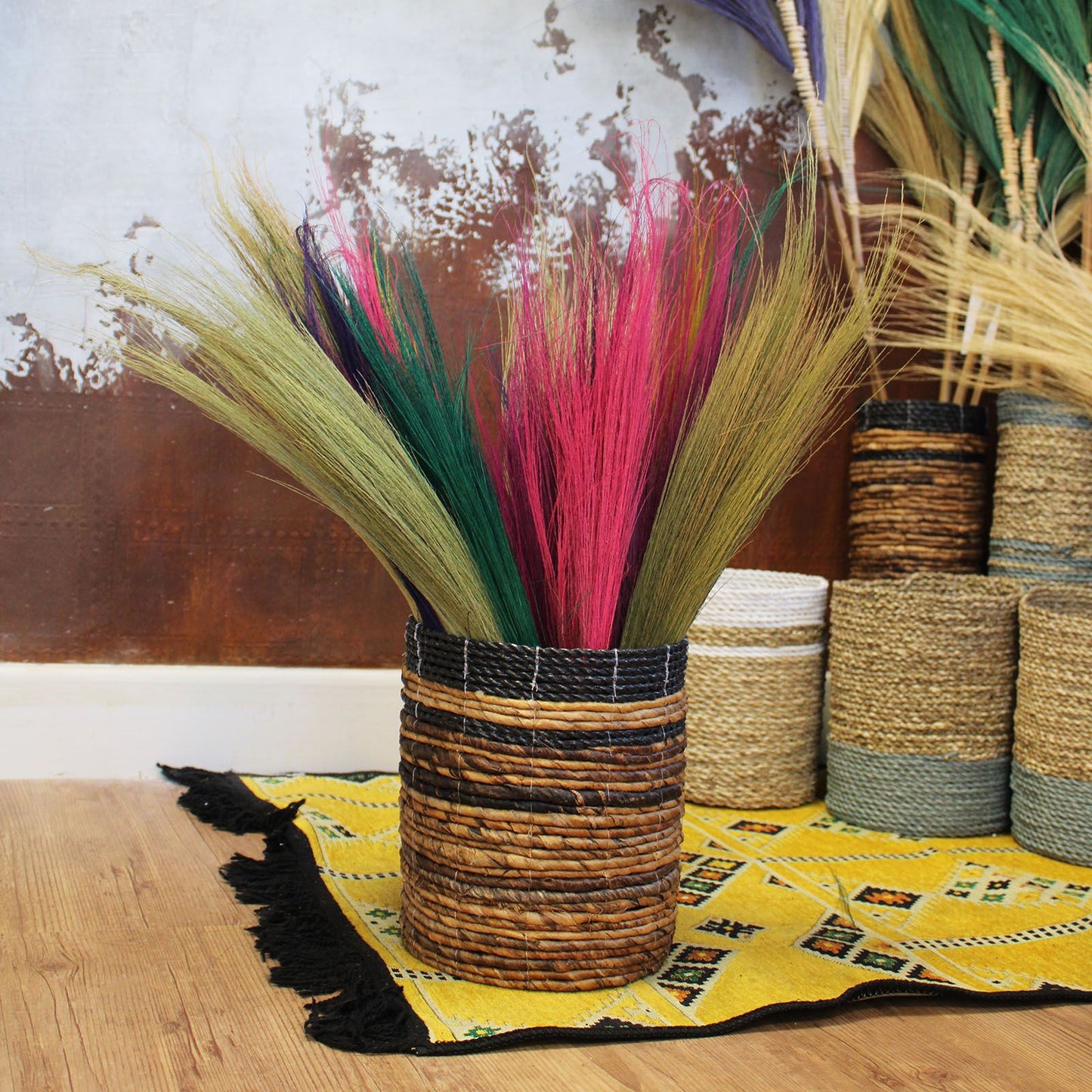 Cesta de mimbre trenzada con tonos naturales y decoraciones en colores vibrantes, ideal para flores secas.