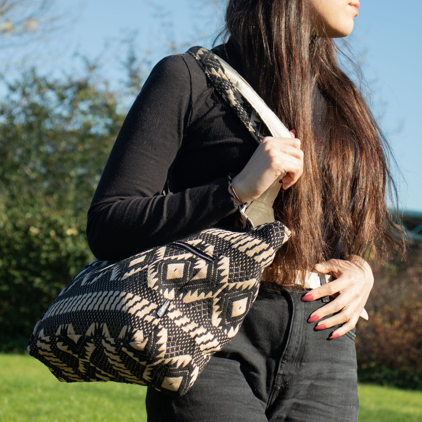 Bolso negro y beige de estilo bohemio, hecho de tela con patrón geométrico y asa larga. Ideal para un look casual.