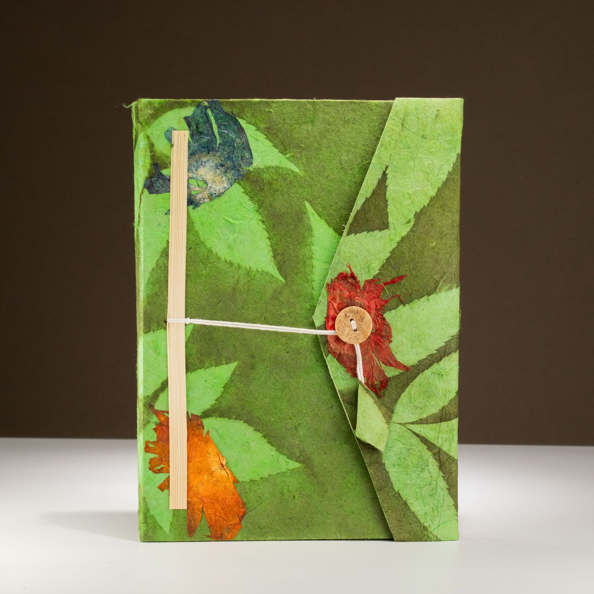 Cuaderno verde de papel reciclado con flores de colores, cierre de cuerda y botón de madera. Ideal para anotaciones.