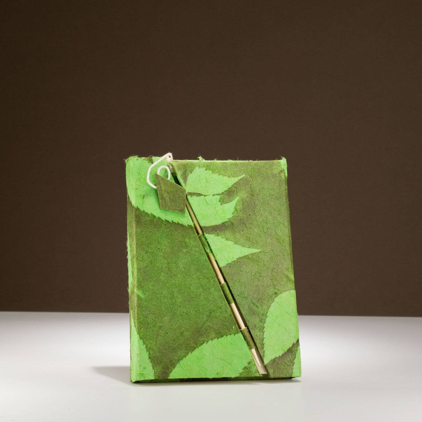 Cuaderno verde de papel reciclado con diseño de hojas, incluye un bolígrafo elegante y ecológico.