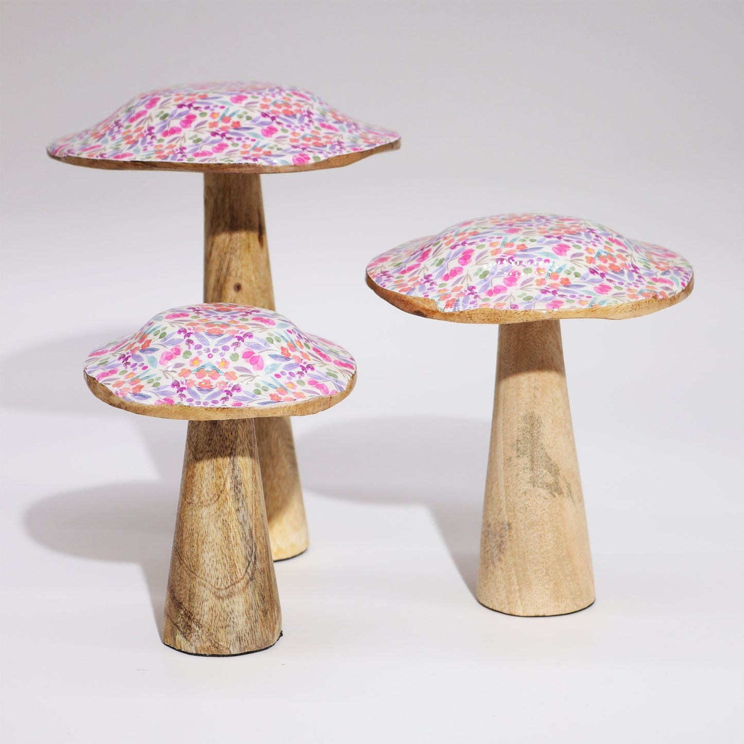 Set de tres hongos decorativos de madera con capuchas en tonos rosa y púrpura, estilo bohemio y artesanal.